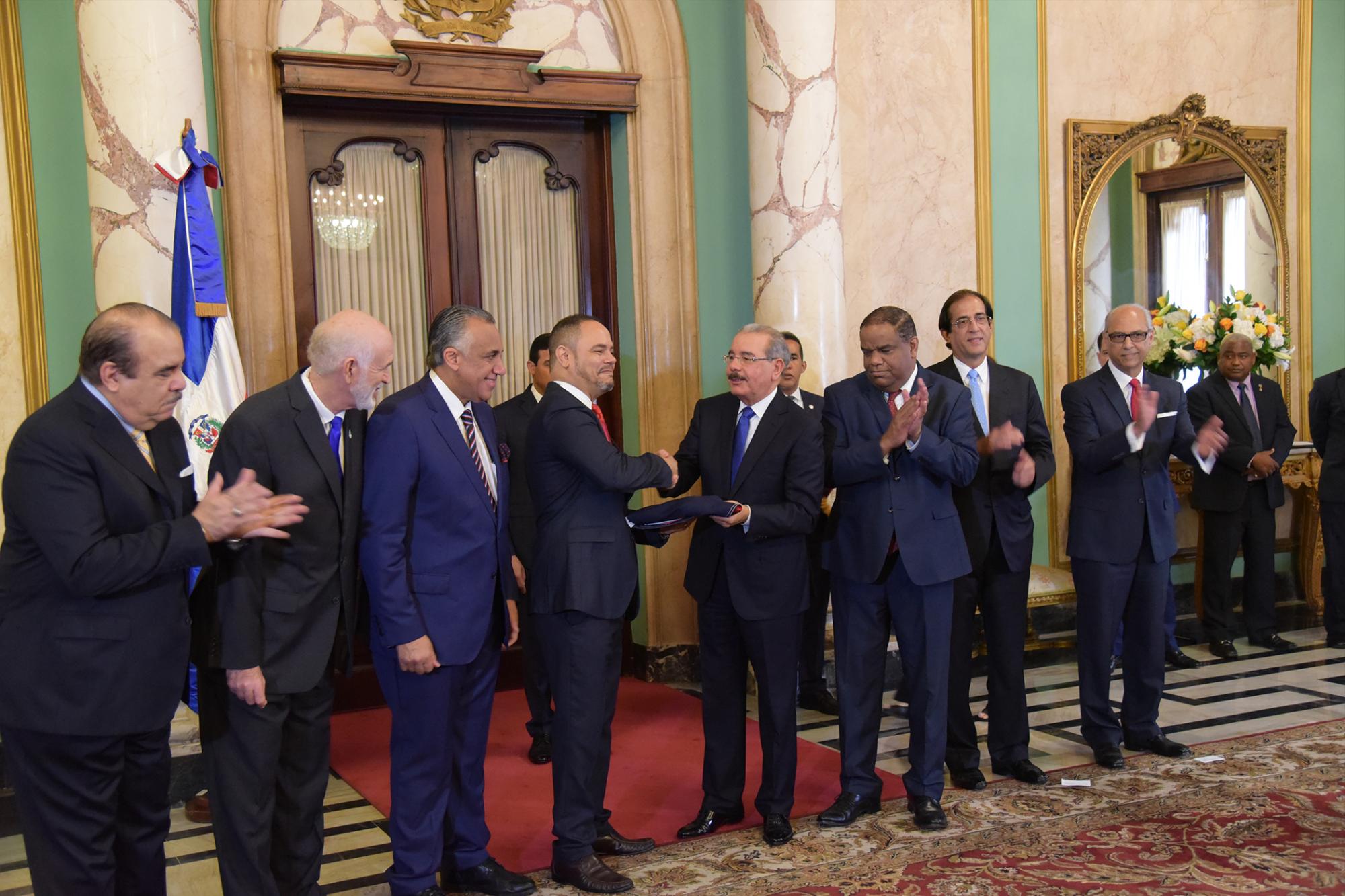 El presidente Danilo Medina le entrega la enseña tricolor al jefe de la misión dominicana para los Juegos Centroamericanos y del Caribe, Barranquilla, 2018, Edwin Rodríguez en un acto en el Salón de Embajadores del Palacio Presidencial, el lunes 16 de julio de 2018.
