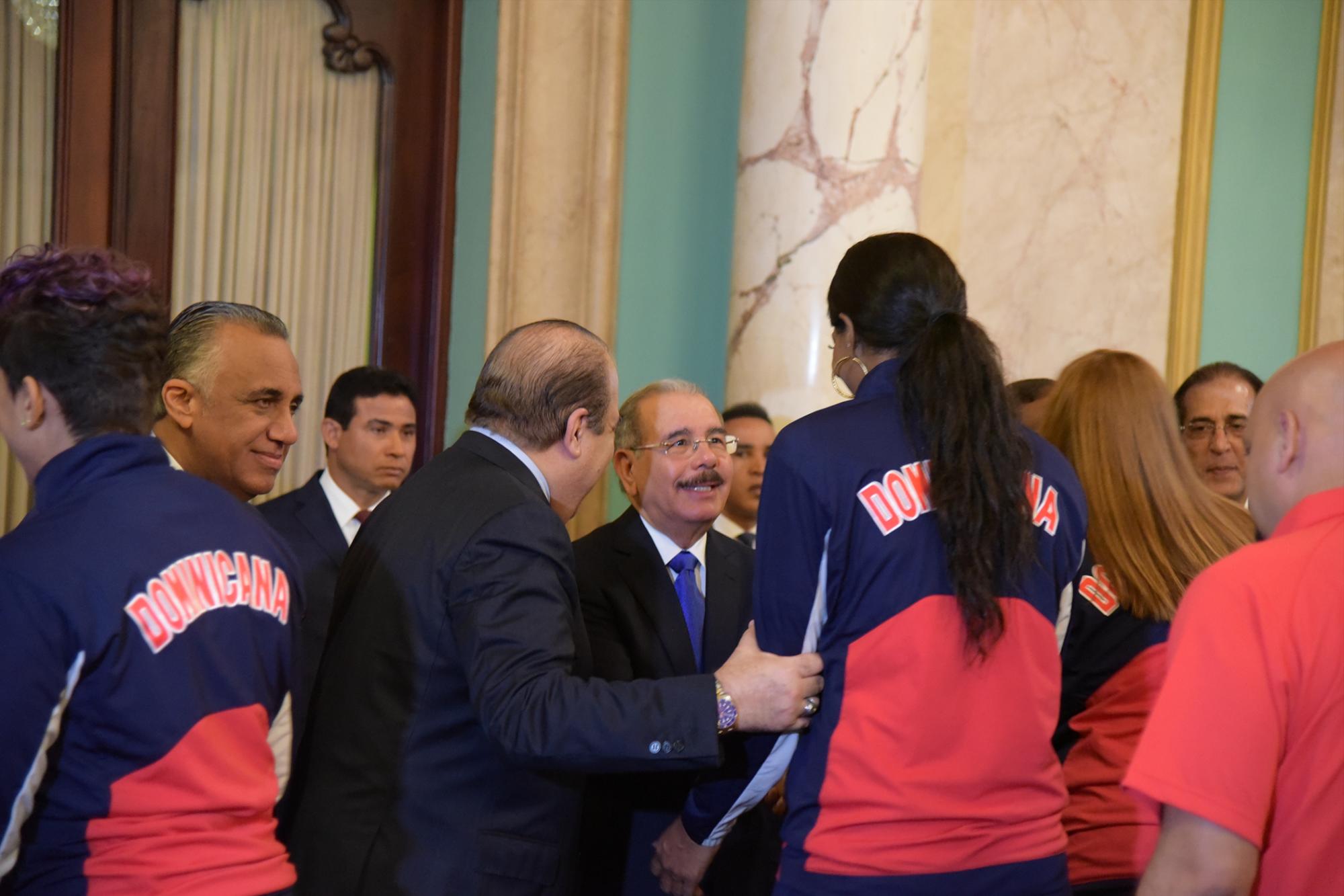 El presidente de la República Danilo Medina, saluda a atletas de voleibol; de espaldas, el director de selecciones nacionales femeninas, Cristóbal Marte, durante la ceremonia de entrega de banderas, el lunes 16 de julio en el Salón de Embajadores del Palacio Presidencial.