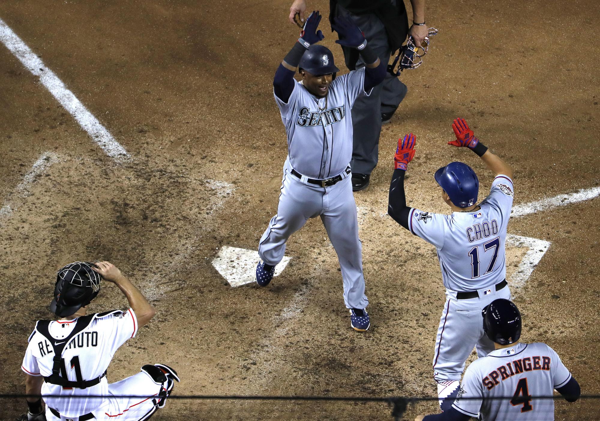 El jugador de la Liga Americana Jean Segura (c) de los Marineros de Seattle es felicitado por Shin-Soo Choo de los Rangers de Texas (2d) luego de un home run de tres carreras hoy, martes 17 de julio de 2018, durante la 89 edición del Juego de las Estrellas de la MLB en el Nationals Park de Washington.