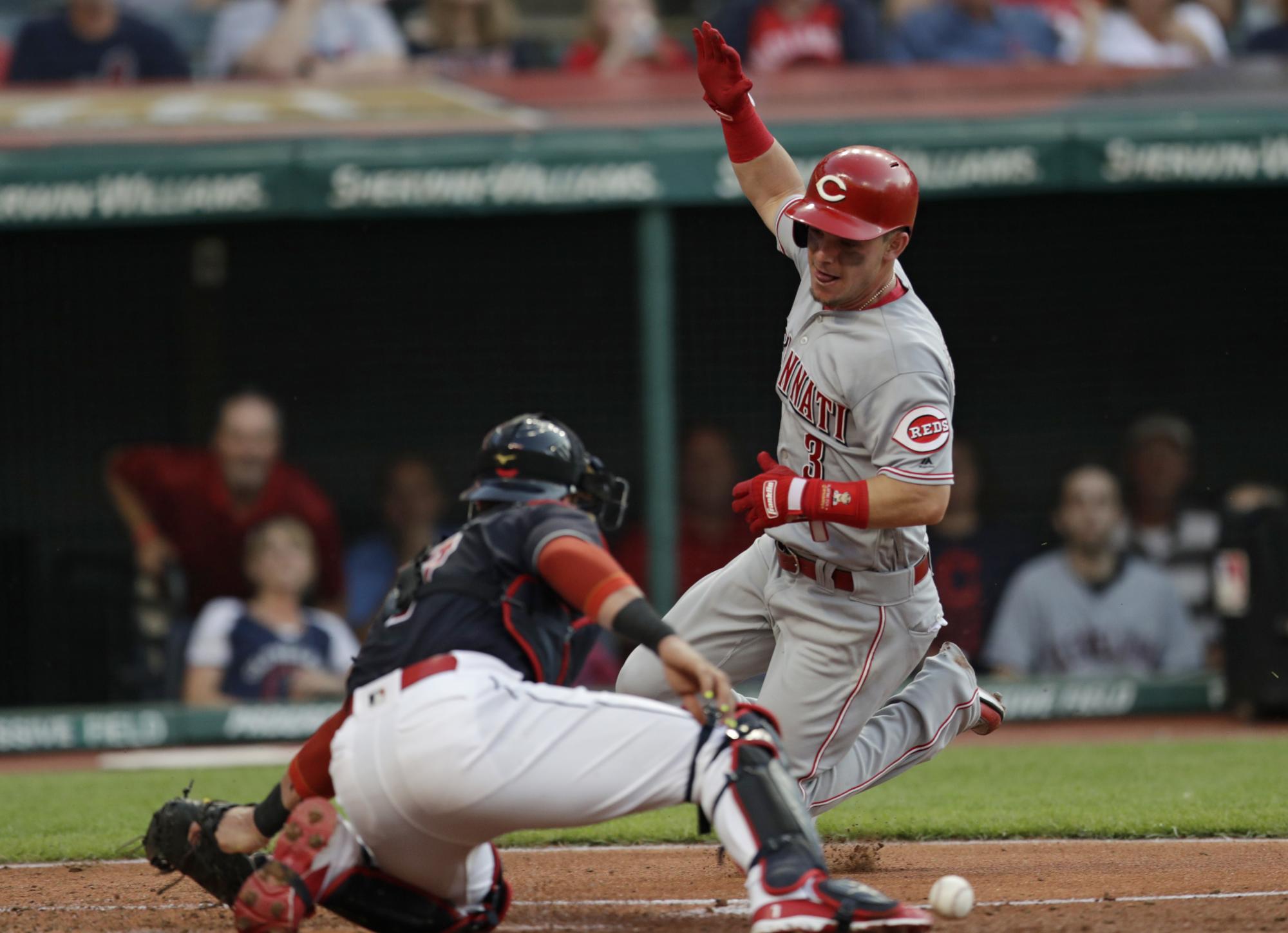 Scooter Gennett, derecha, de los Rojos de Cincinnati se barre en el plato para anotar una carrera mientras el receptor de los Indios de Cleveland, el brasileño Yan Gomes, no puede quedarse con la pelota, el lunes 9 de julio de 2018, en Cleveland.