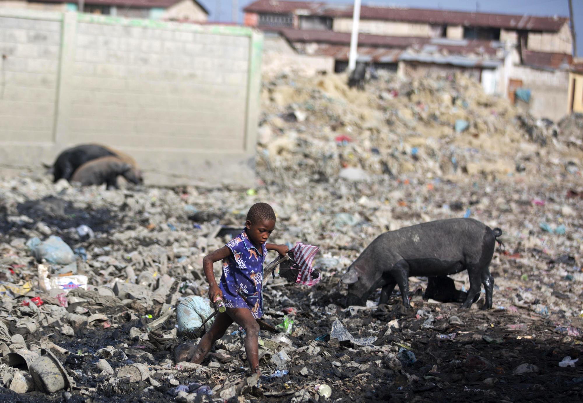 En esta foto del 18 de julio de 2018, un joven camina a través de la basura cerca de su casa en el barrio pobre Cite Soleil de Puerto Príncipe, Haití. 