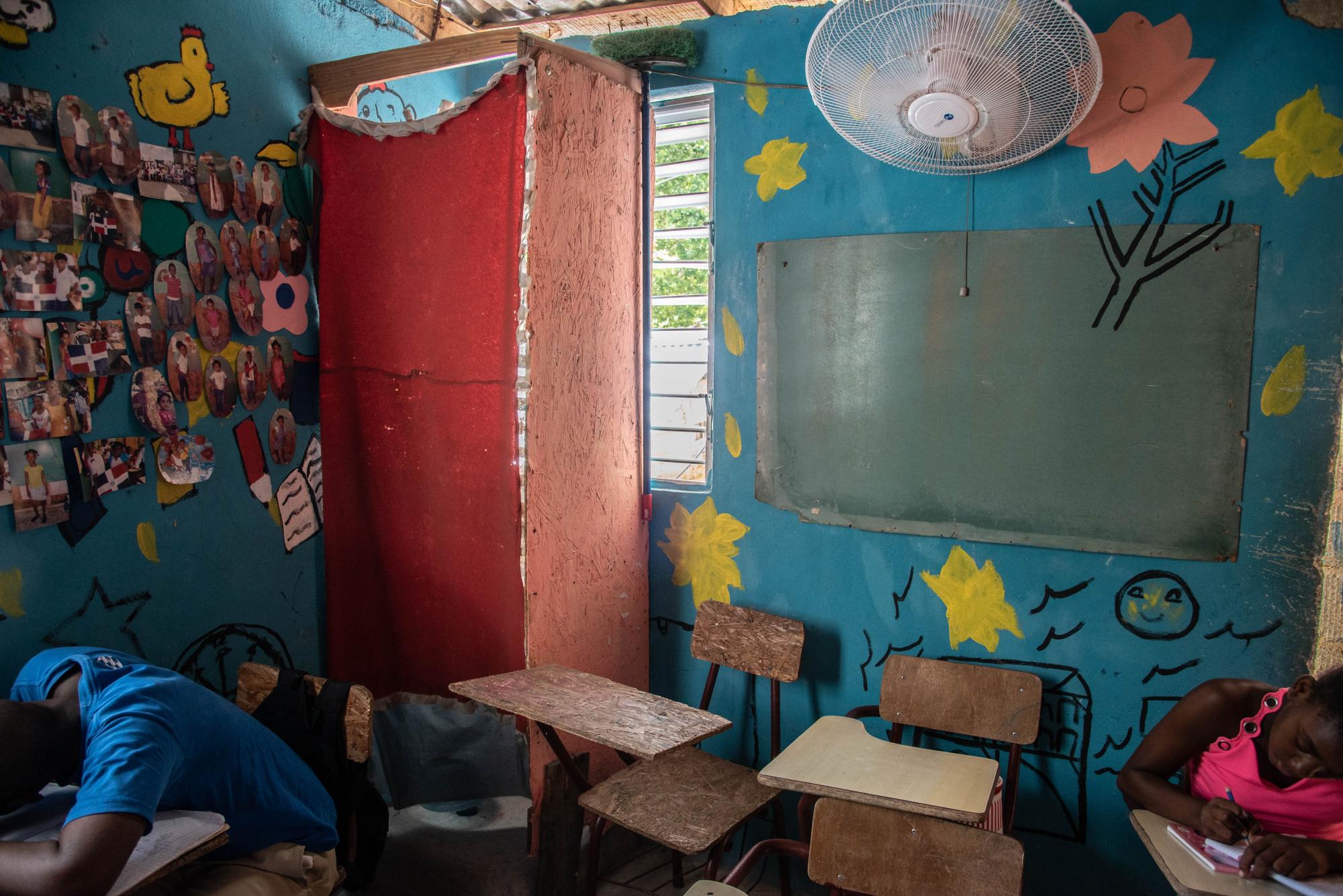 En la esquina, encerrada con una cortina roja, está una letrina improvisada para los estudiantes de una sala de tareas en El Dique.