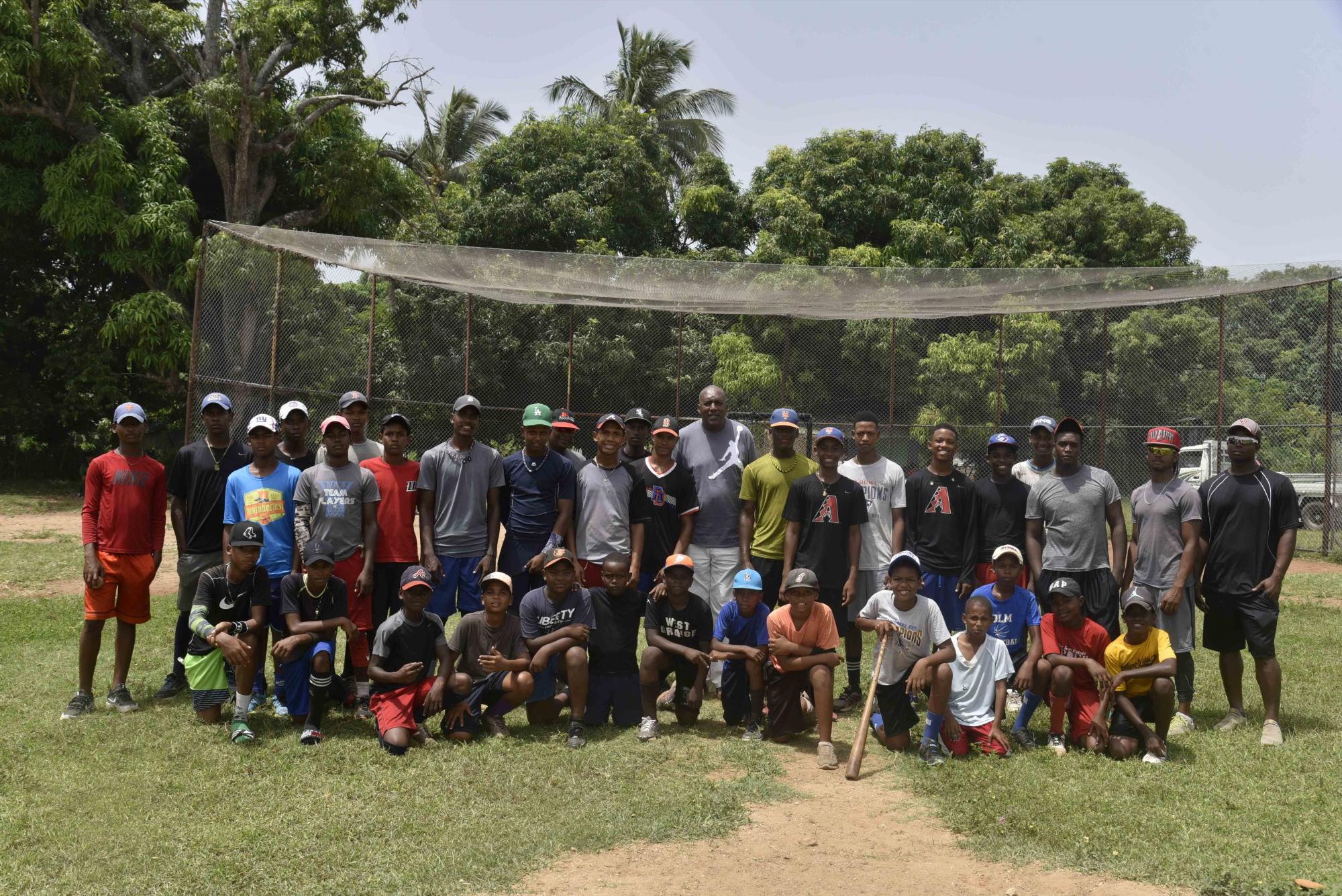 Chicho posando con los muchachos que practican béisbol en la Fundación