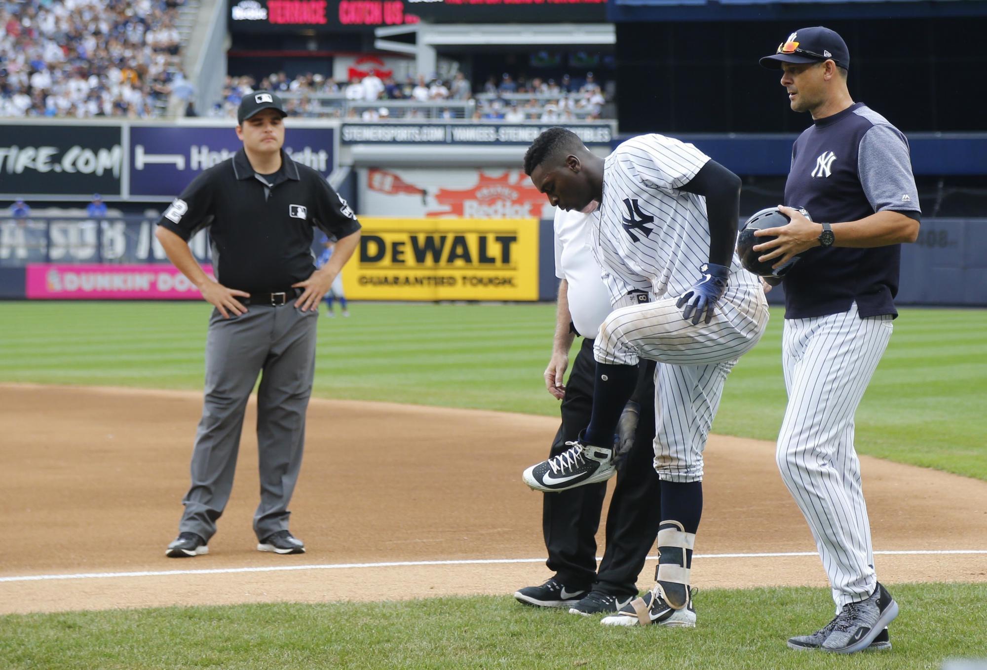 El preparador físico Steve Donohue (tercero a la derecha) y el manager Aaron Boone (derecha) auxilian a Didi Gregorius de los Yanquis de Nueva York tras una colisión con Kendrys Morales (no aparece) de los Azulejos de Toronto, el domingo 19 de agosto de 2018.