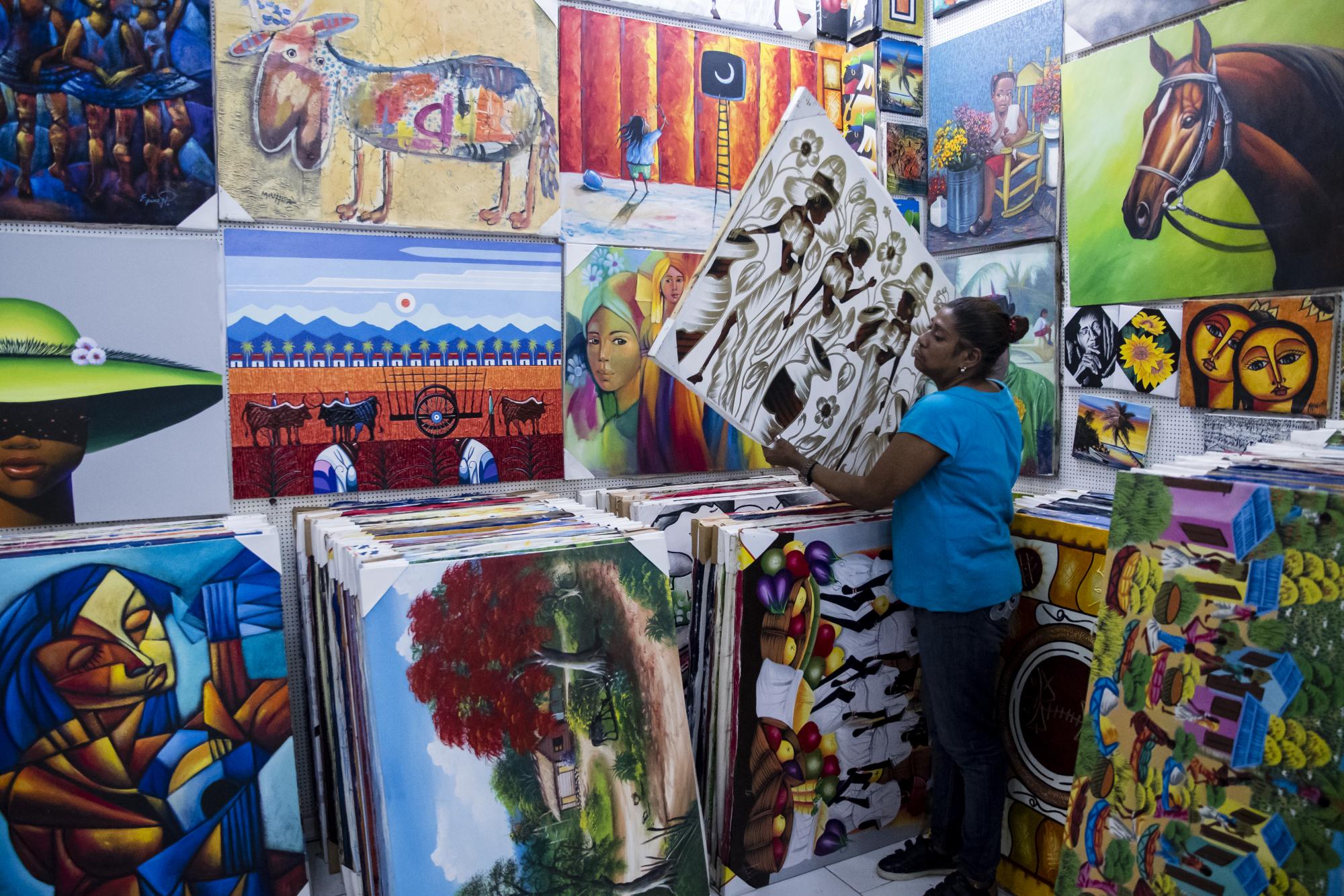 Una de las vendedoras muestra pinturas a reporteros de Diario Libre 