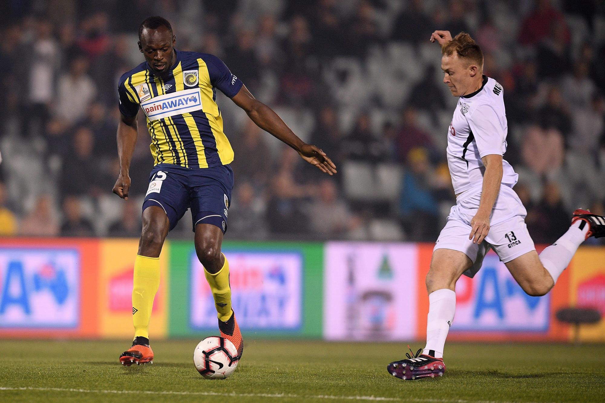 El jugador de los Marineros y ex atleta jamaicano Usain Bolt (i) disputa el balón con Nathan Millgate durante el partido de la Liga Australiana de fútbol que enfrentó a los Marineros y el Macarthur Sur West United, en el estadio Campbelltown de Sídney (Australia), el 12 de octubre de 2018.