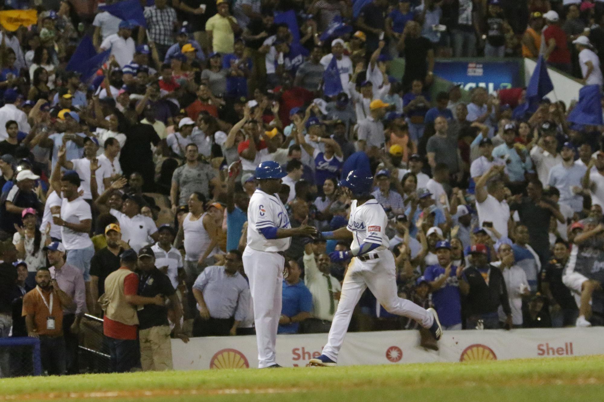 Pablo Reyes saluda al coach de tercera base, Héctor de la Cruz, luego de su jonrón de tres carreras en el cuarto episodio ante el lanzador Félix Paulino de las Águilas Cibaeñas, la noche del martes 30 de octubre en el Estadio Quisqueya.