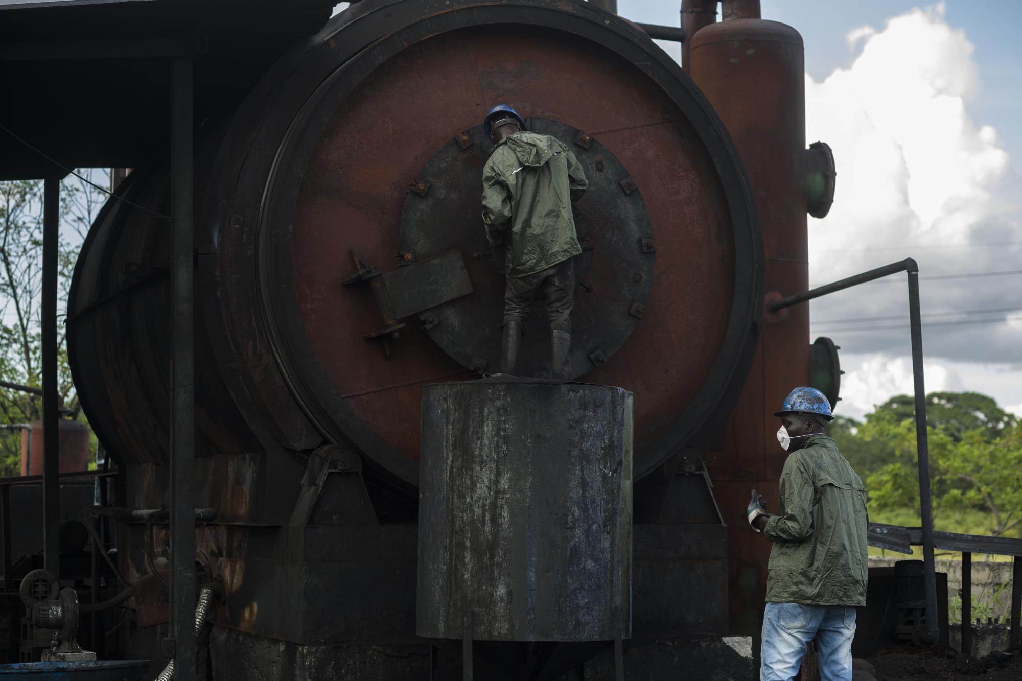 Empleados en la planta de gomas desechadas verifican el funcionamiento de la máquina.