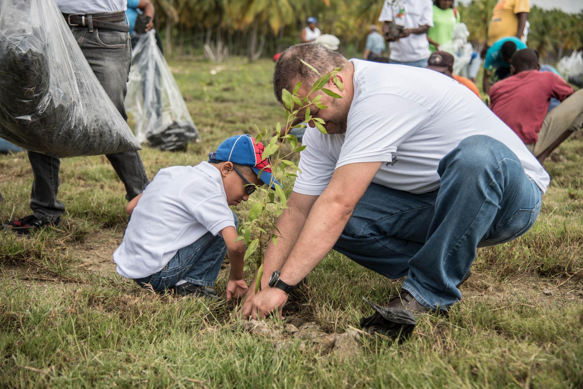 Un niño especial del CAID siembra un árbol junto a un familiar.