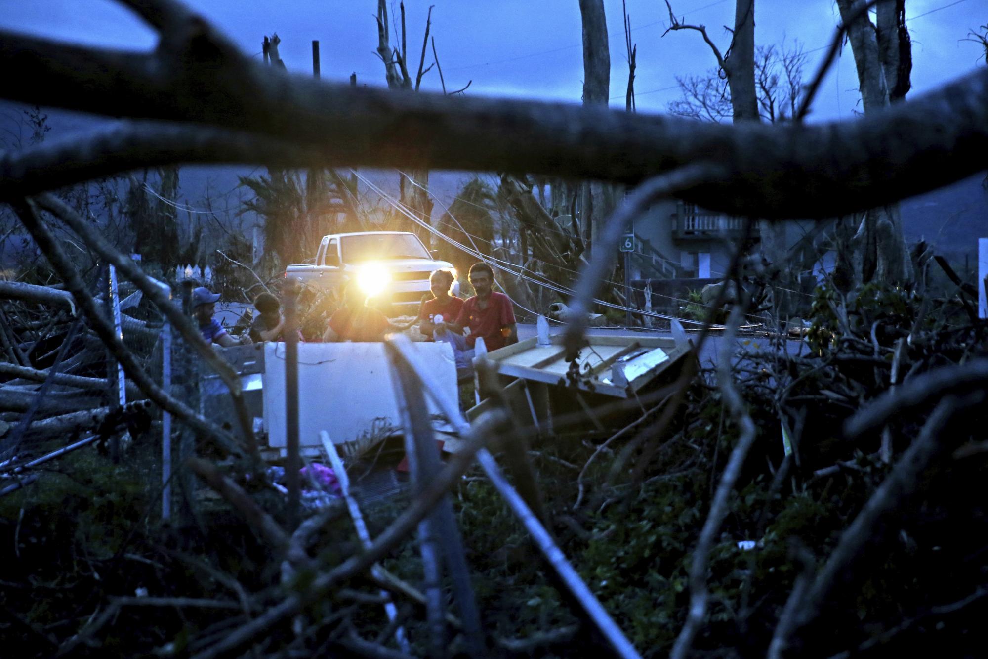 En esta imagen de archivo, tomada el 26 de septiembre de 2017, Evan Mandino (derecha) se sienta con sus vecinos en un sofá en el exterior de sus casas, destruidas tras el paso del huracán María, en Yabucoa, Puerto Rico.