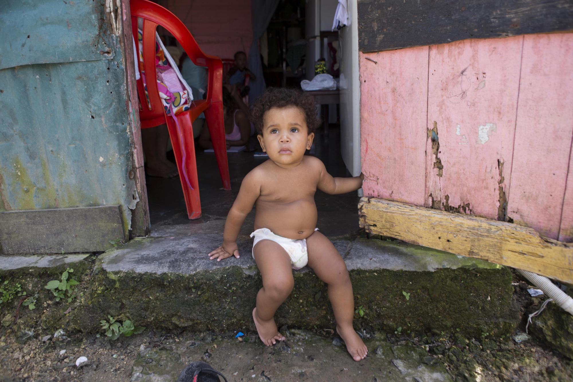 Un niño sentado en la puerta de su casa en Villa Heloisa, en el sector de Las Cañitas, a orillas del río Ozama, en Santo Domingo (República Dominicana). 