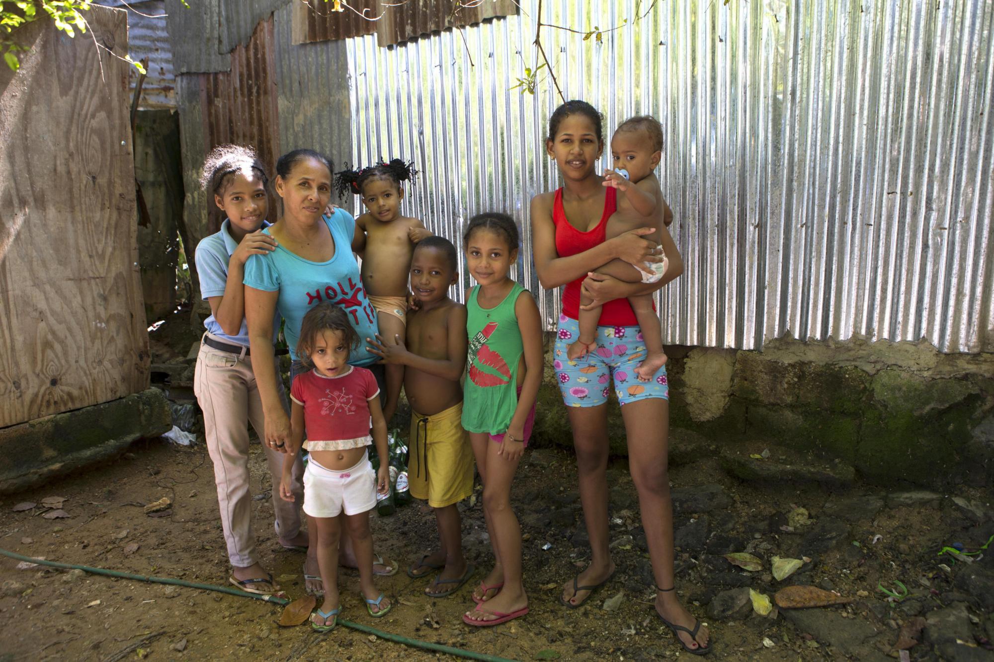 Miriam (2i), de cuarenta y tres años, junto a sus hijas y nietos, por quienes lucha para salir adelante vendiendo helados y bebidas en su propia casa en Villa Heloisa, en el sector de Las Cañitas, a orillas del río Ozama, en Santo Domingo.