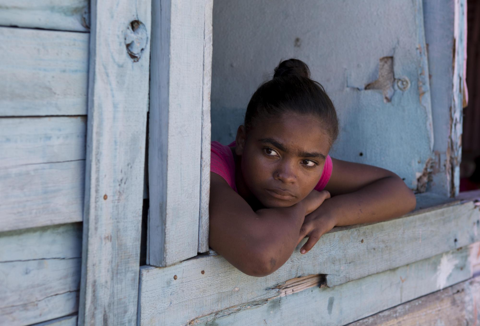 Una joven mientras observa la calle desde su casa en el albergue de Canta La Rana, en el municipio dominicano de Los Alcarrizos, en Santo Domingo (República Dominicana). 