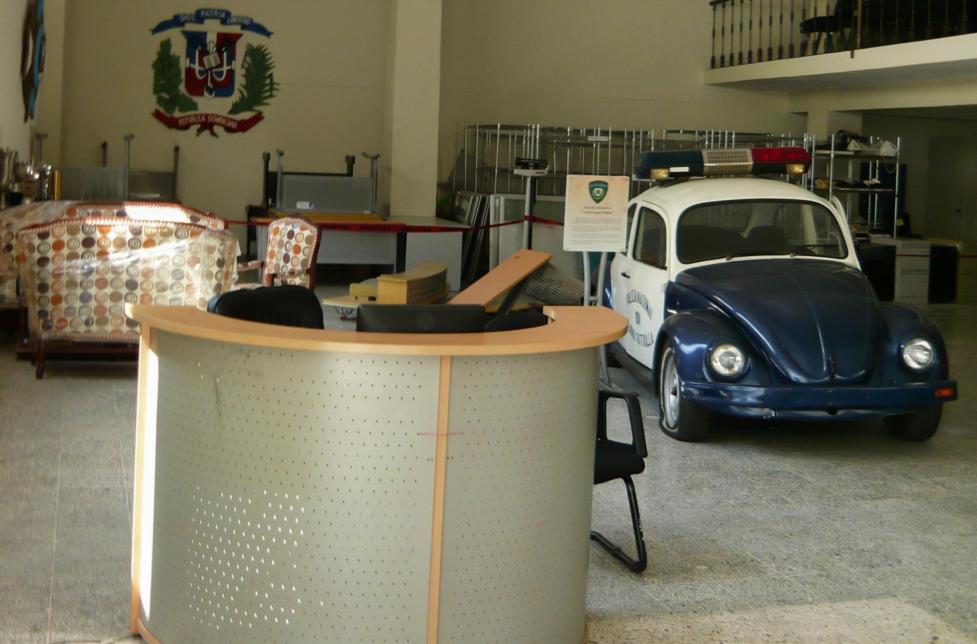 Vista del primer nivel del museo donde se ve la recepción, el viejo Volkswagen y mobiliario de oficina apilado.