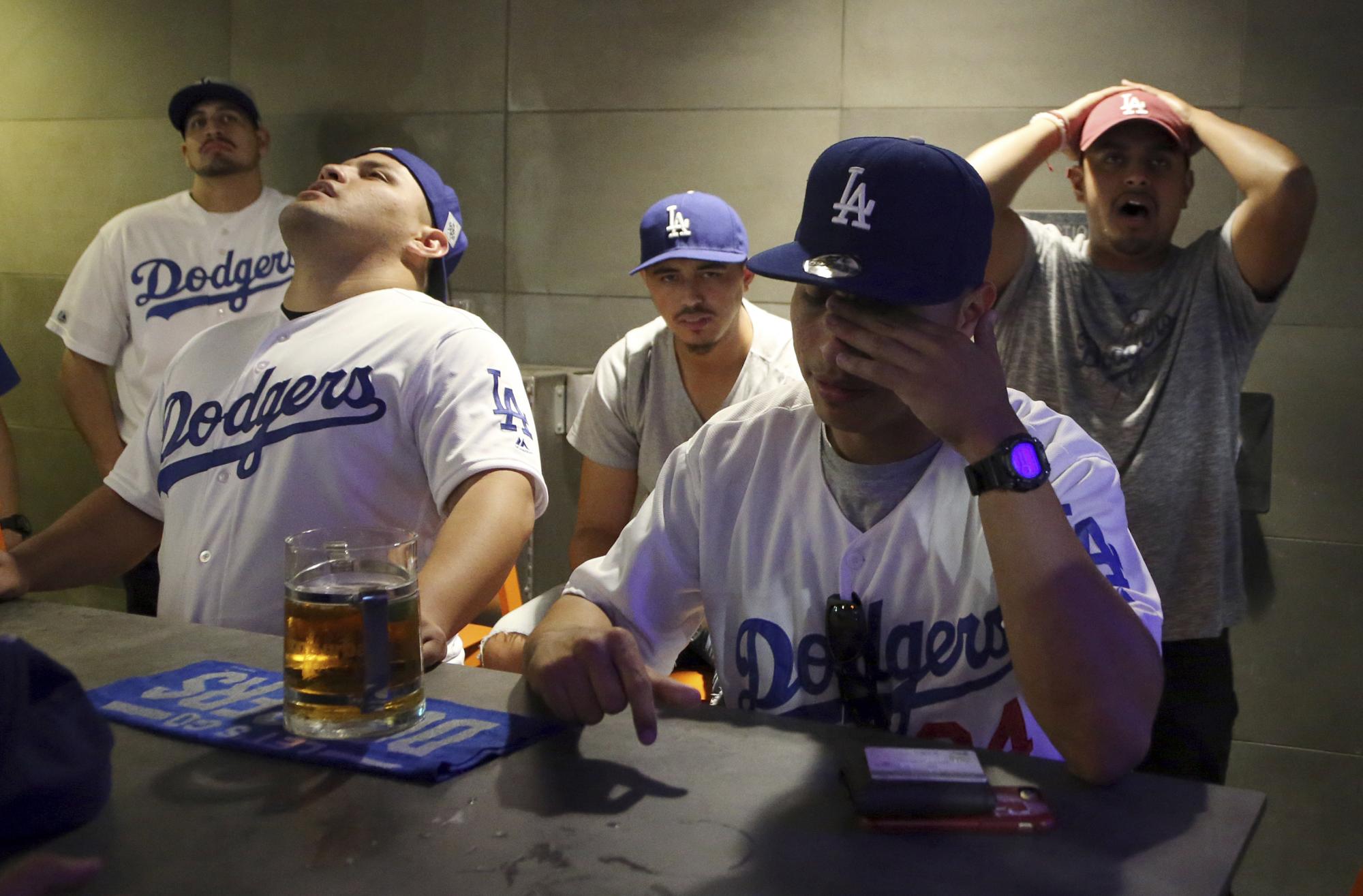 Fanáticos de los Dodgers, sentados desde la izquierda, Roberto Rosa y Gabriel Chulo, y Andy Tobias, atrás, reaccionan a la derrota 5-1 de su equipo en el restaurante y bar Tom’s Urban en el complejo de entretenimiento LA Live en el centro de Los Ángeles en el decisivo juego 7 de la Serie Mundial entre los Dodgers de Los Angeles y los Astros de Houston, el miércoles, 1 de noviembre de 2017.