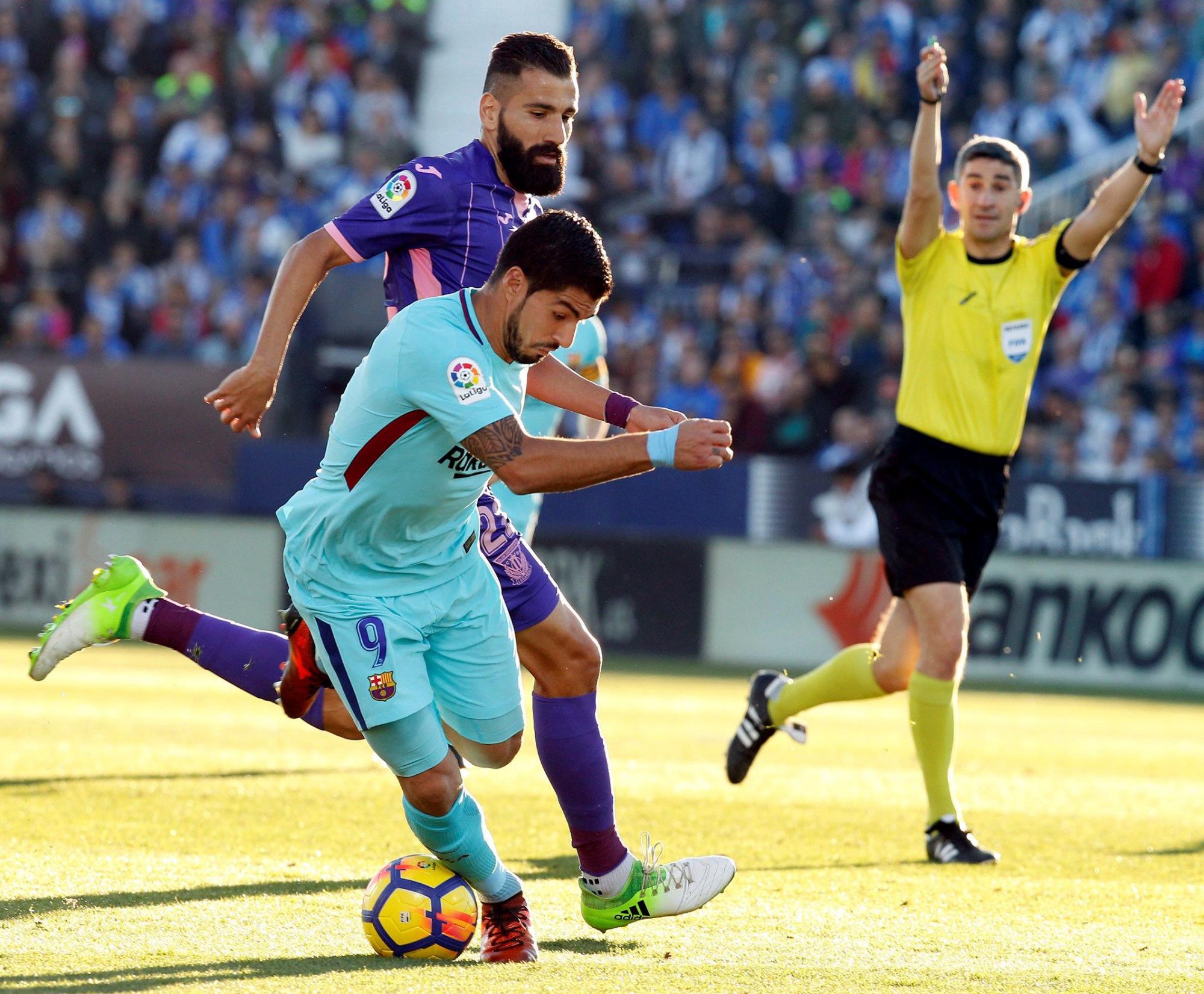 El delantero uruguayo del Barcelona Luis Suárez (i) disputa un balón con el defensa griego del Leganés Dimitrios Siovas (c) durante el partido correspondiente a la duodécima jornada de LaLiga Santander disputado hoy en el estadio de Butarque.
