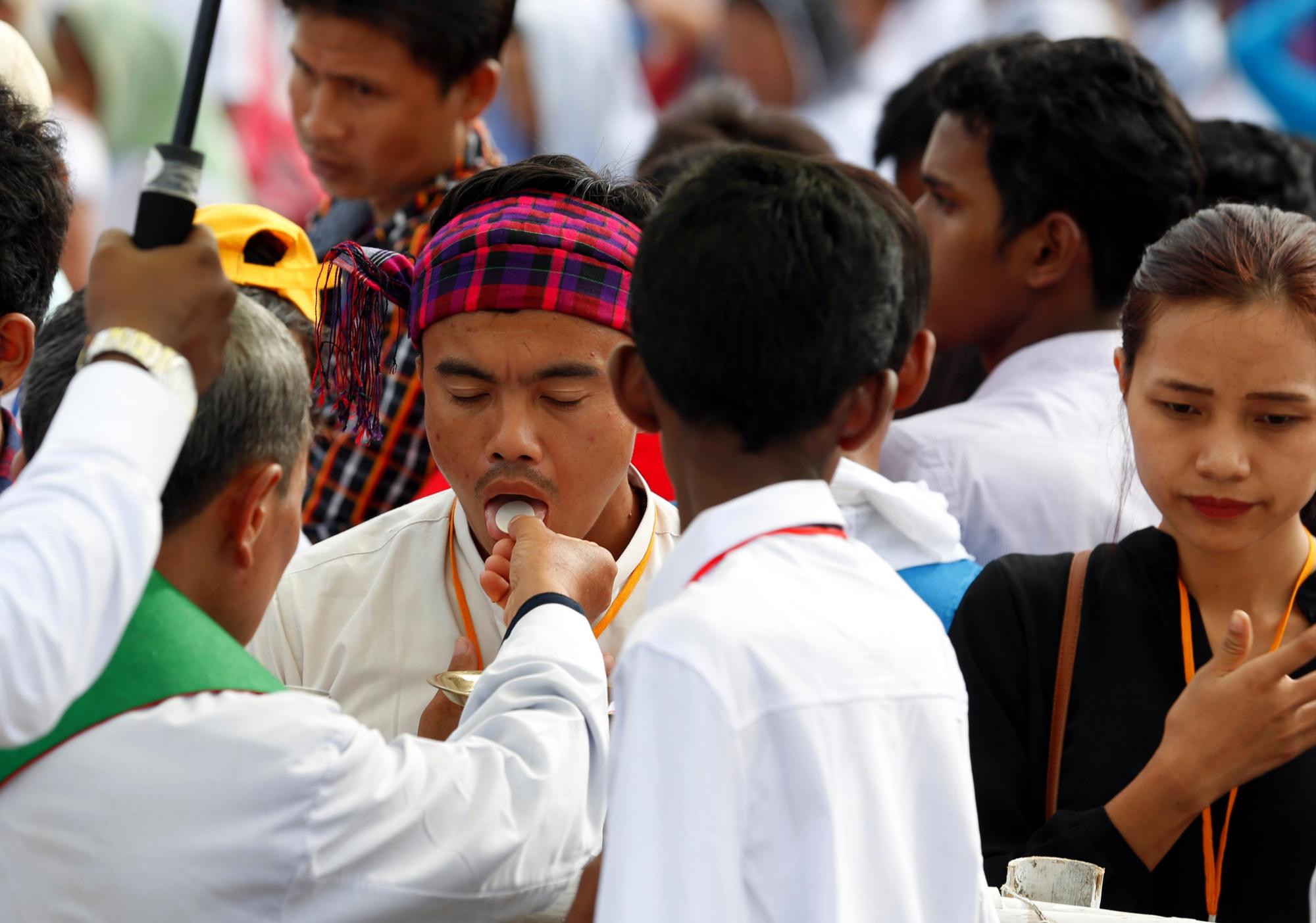 Fieles comulgan durante una misa oficiada por el papa Francisco en Rangún (Birmania) hoy, 29 de noviembre de 2017. El papa Francisco celebró hoy una misa campal en Rangún a la que acudieron cerca de 150.000 fieles y en su homilía elogió la ayuda, sin distinción de religión y etnias, de la pequeña comunidad católica presente en Birmania.