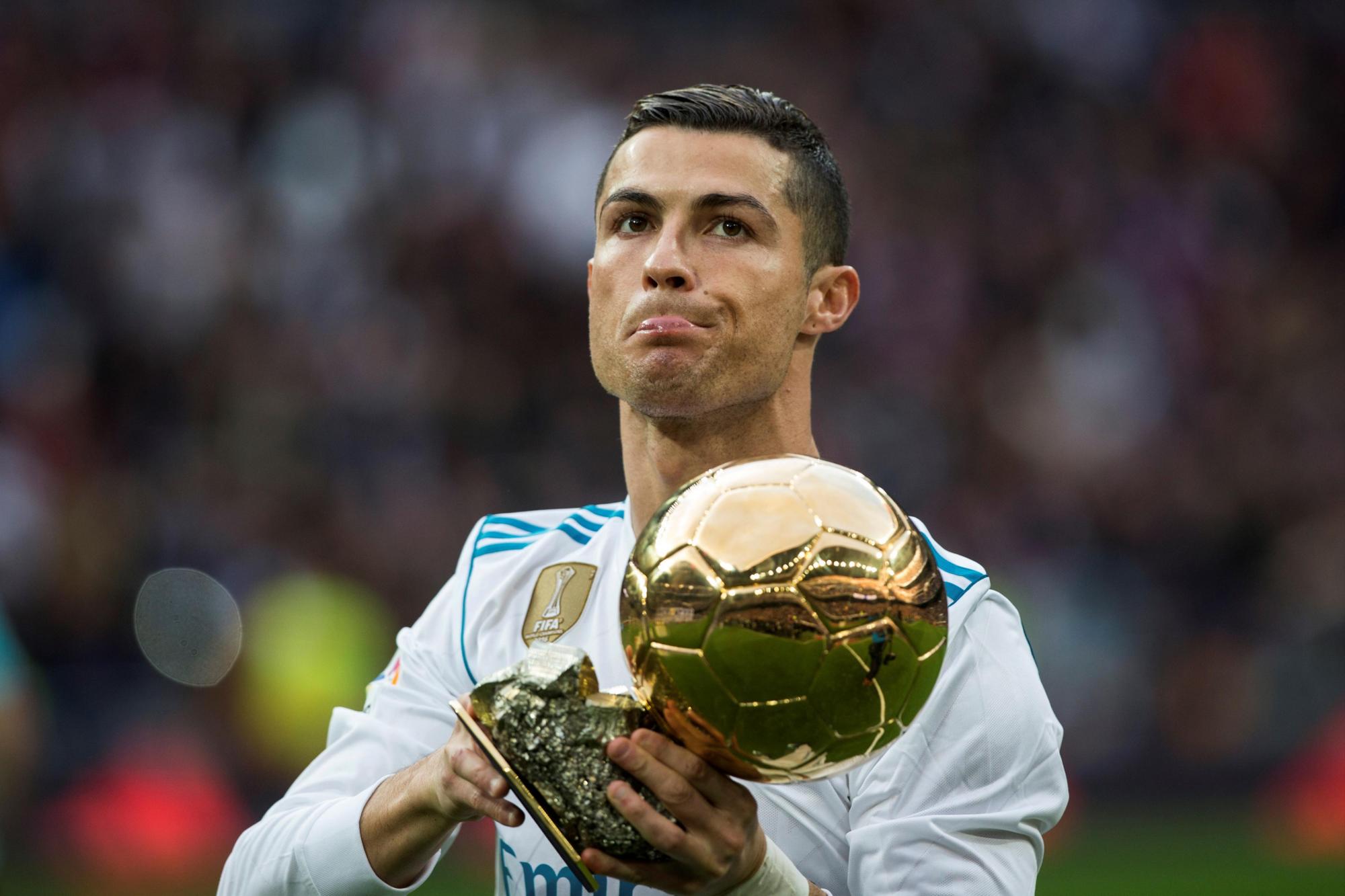 El delantero portugués del Real Madrid Cristiano Ronaldo muestra el trofeo del Balón de Oro antes del partido de liga ante el Sevilla en el estadio Santiago Bernabeu.