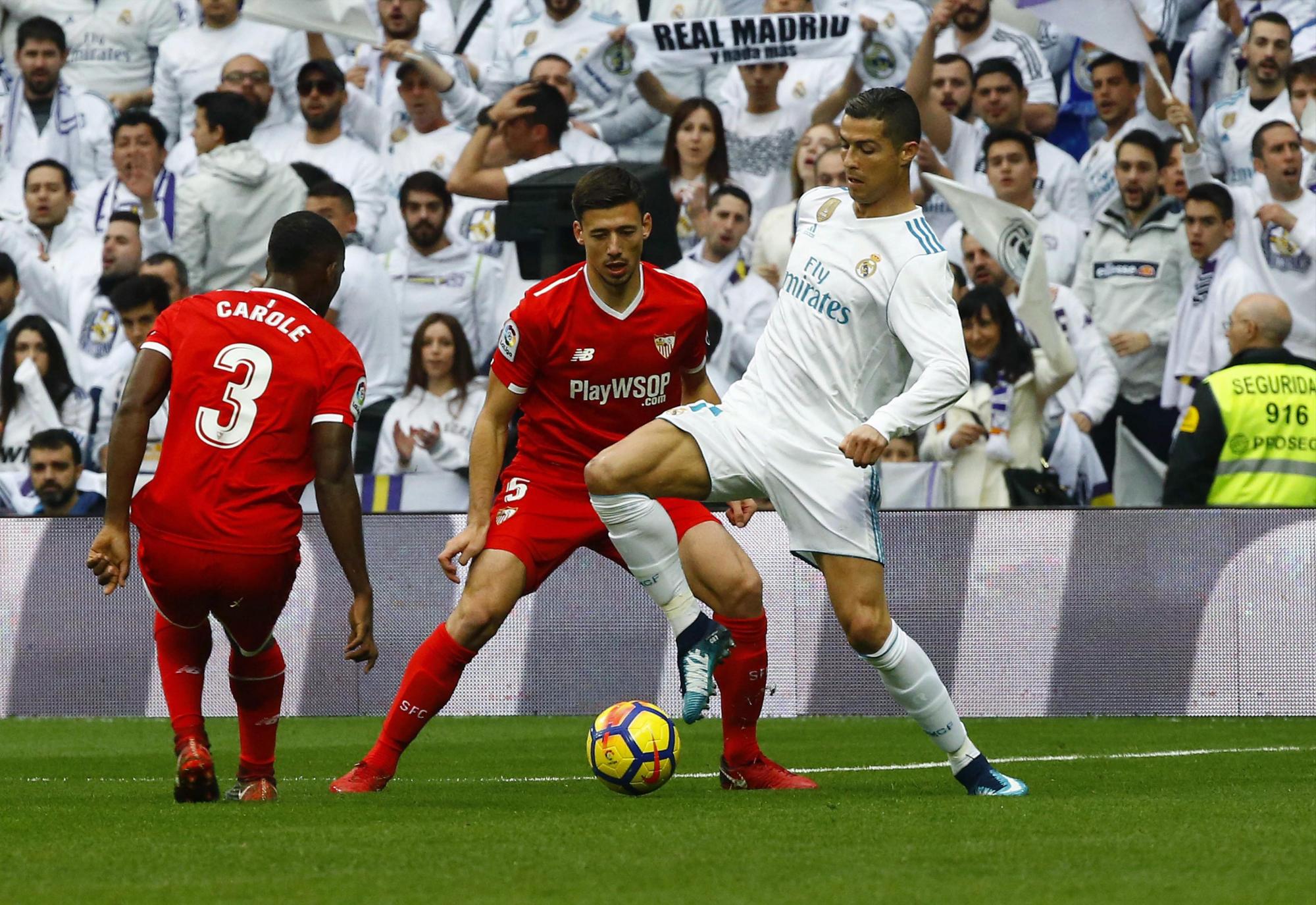 El delantero portugués del Real Madrid Cristiano Ronaldo (d) pelea un balón con los jugadores del Sevilla Clement Lenglet (c) y Lionel Carole, en el partido de la decimoquinta jornada de liga que se disputa en el estadio Santiago Bernabéu.