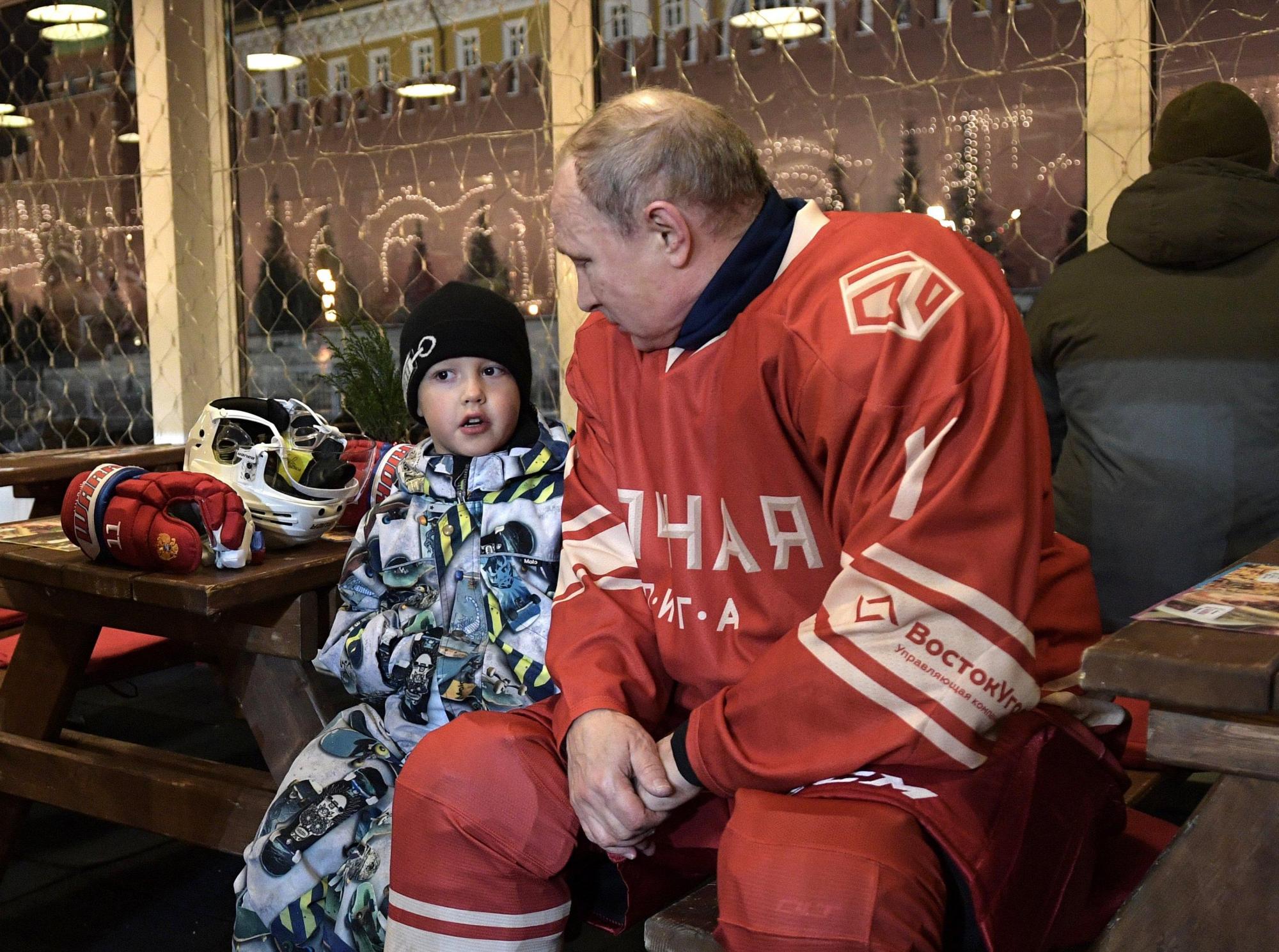 El presidente ruso, Vladimir Putin (R), habla con un niño durante un descanso del partido de la Liga de Hockey Nocturno en la pista de patinaje GUM en la Plaza Roja de Moscú, Rusia, el 22 de diciembre 2017.