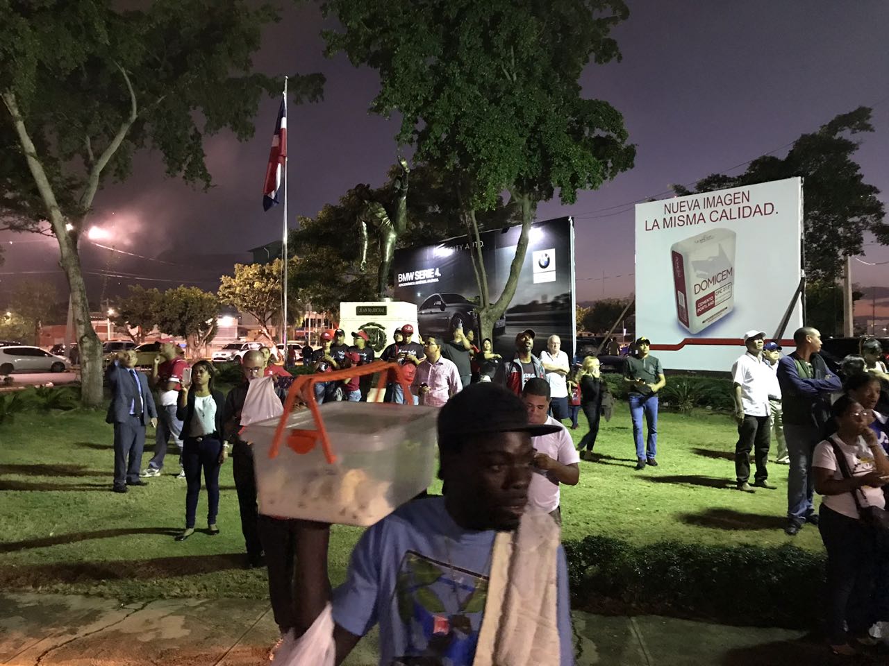 Fanáticos, personal de estadio y vendedores observan desde lejos el incendio.