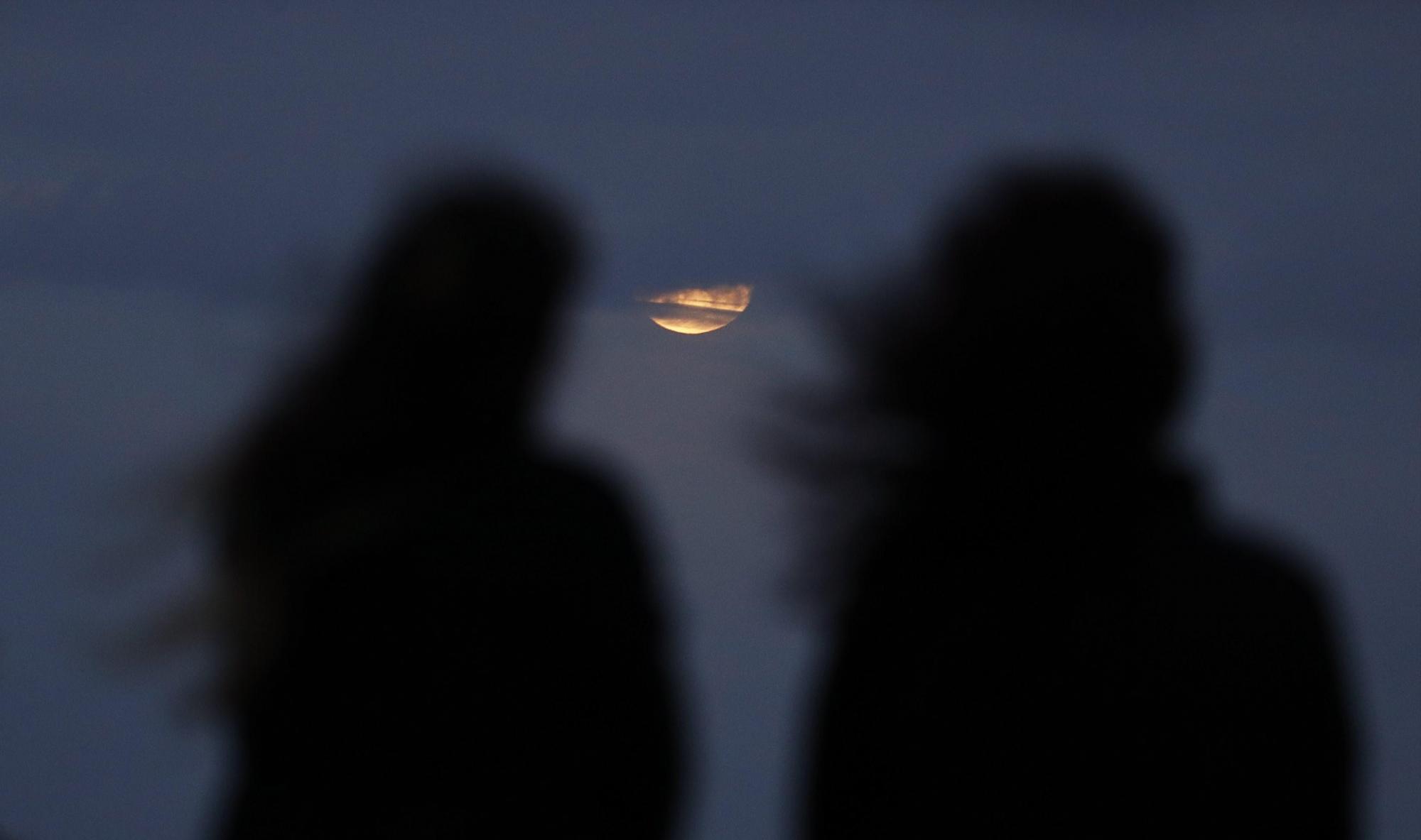 Dos mujeres observan la luna cerca de la playa Bondi en Sídney (Australia) hoy, 31 de enero de 2018. Los habitantes de gran parte del planeta apreciarán el 31 de enero un eclipse total de la llamada superluna azul, la segunda luna llena del mes y en su posición más cercana a la Tierra. 