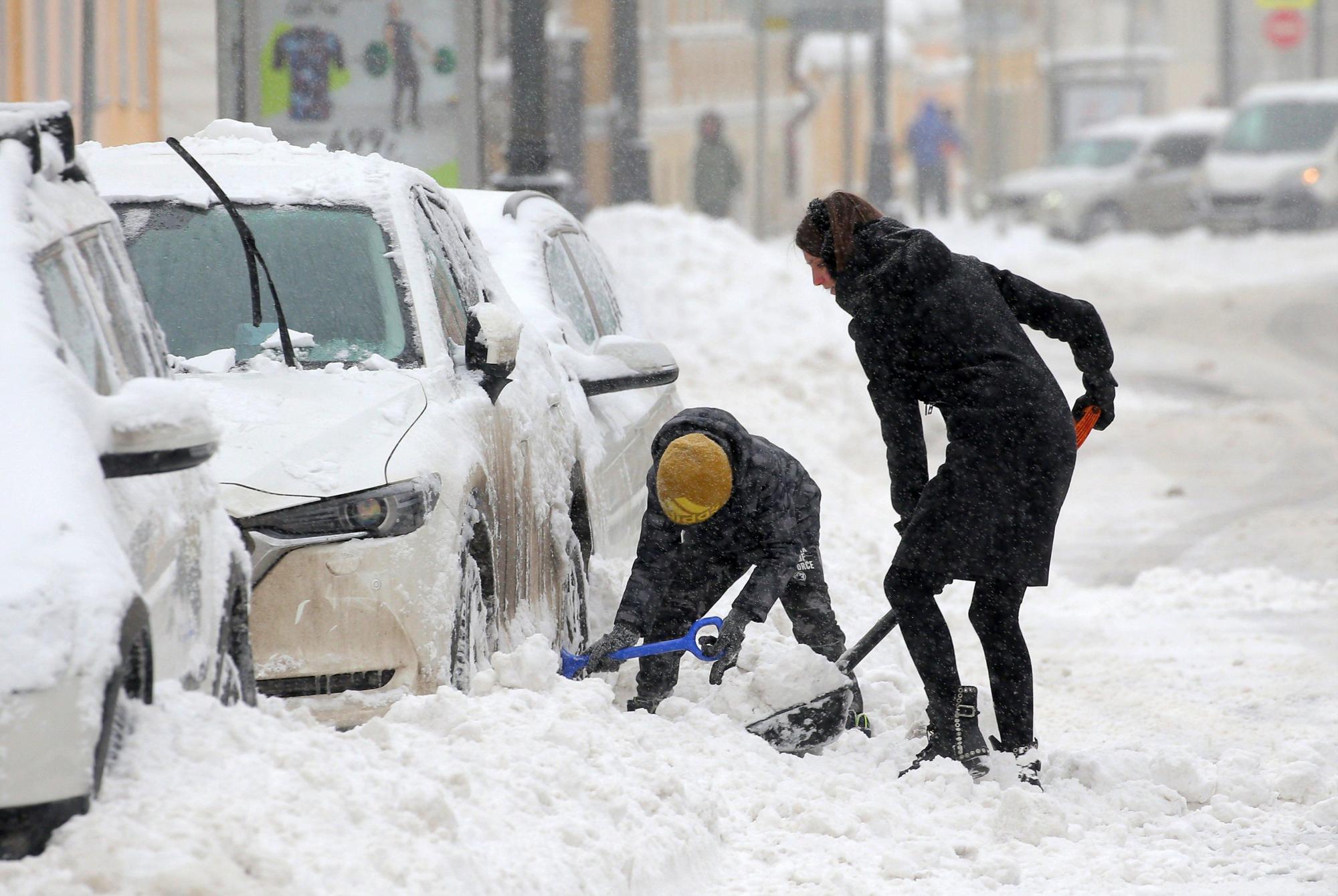Una mujer cava para retirar la nieve de su vehículo durante la fuerte nevada en Moscú, en Rusia este domingo 04 de febrero de 2018. 
