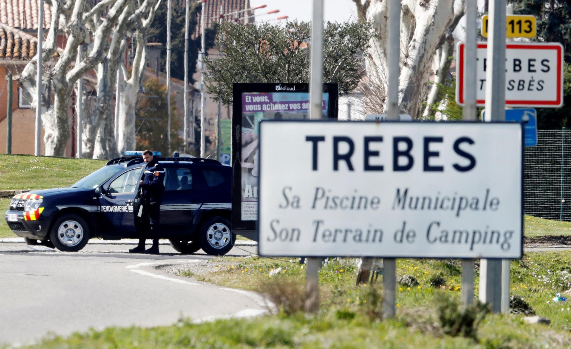 Vehículos de la Gendarmería Nacional francesa permanecen aparcados a la entrada de la localidad de Trebes (Francia) donde se ha producido una toma de rehenes.