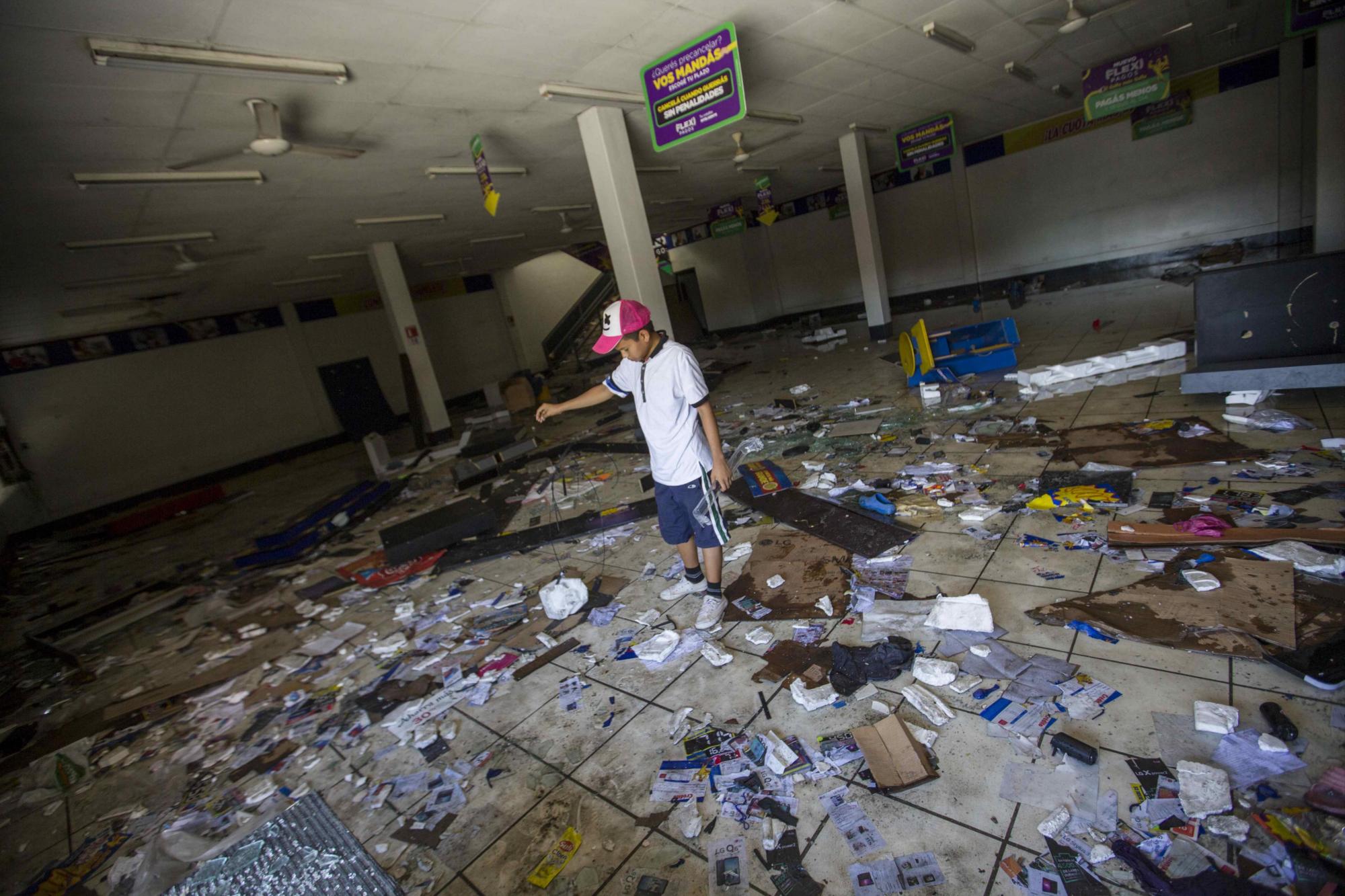  Un joven recoge objetos dejados tras saqueos en un supermercado hoy, 23 de abril de 2018, durante el sexto día de protestas en Managua (Nicaragua). Los enfrentamientos entre estudiantes y la Policía de Nicaragua no han cesado en la capital, donde se espera hoy una gran marcha por la paz y el diálogo convocada por los empresarios, en medio de protestas contra el Gobierno que llegan ya a su sexto día y han dejando al menos 27 muertos, centenares de heridos y destrucción de comercios. EFE/Jorge Torres
