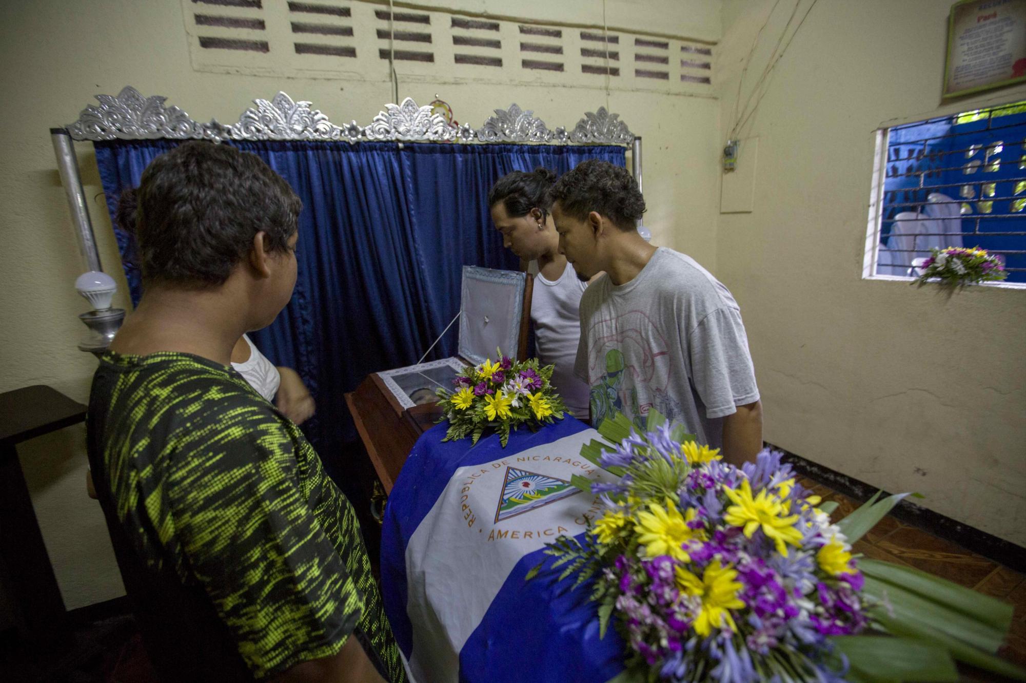 Un grupo de personas observa el ataúd de Dani Stalin Rivas, que murió durante las protestas contra las reformas del instituto Nicaragüense de Seguridad Social (INSS) hoy, 23 de abril de 2018, en Managua (Nicaragua). Los enfrentamientos entre estudiantes y la Policía de Nicaragua no han cesado en la capital, donde se espera hoy una gran marcha por la paz y el diálogo convocada por los empresarios, en medio de protestas contra el Gobierno que llegan ya a su sexto día y han dejando al menos 27 muertos, centenares de heridos y destrucción de comercios. EFE/Jorge Torres