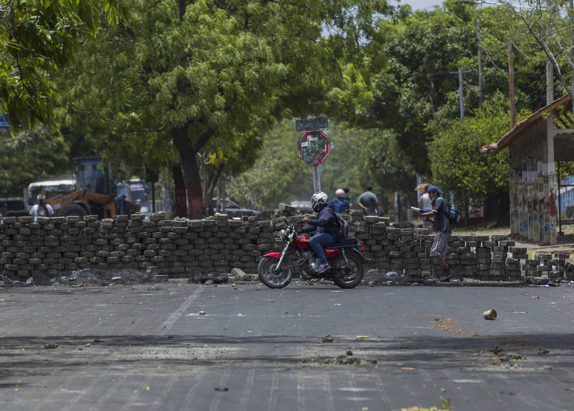 Un motociclista pasa frente a una barricada hoy, 23 de abril de 2018, durante protestas en Managua (Nicaragua). Los enfrentamientos entre estudiantes y la Policía de Nicaragua no han cesado en la capital, donde se espera hoy una gran marcha por la paz y el diálogo convocada por los empresarios, en medio de protestas contra el Gobierno que llegan ya a su sexto día y han dejando al menos 27 muertos, centenares de heridos y destrucción de comercios. EFE/Jorge Torres