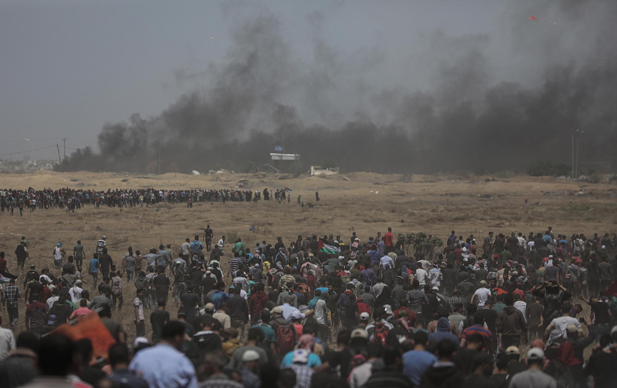 Cientos de palestinos congregados durante los enfrentamientos surgidos tras las protestas convocadas cerca de la frontera con Israel en el este de la franja de Gaza, hoy, 14 de mayo de 2018.  