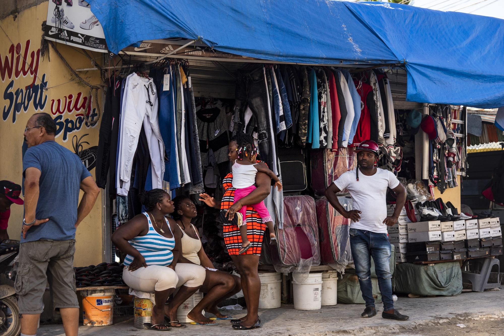 Mientras esperan la llegada de algún cliente, estas vendedoras conversan entre ellas bajo la penumbra de la noche que se avecina en las calles de Friusa