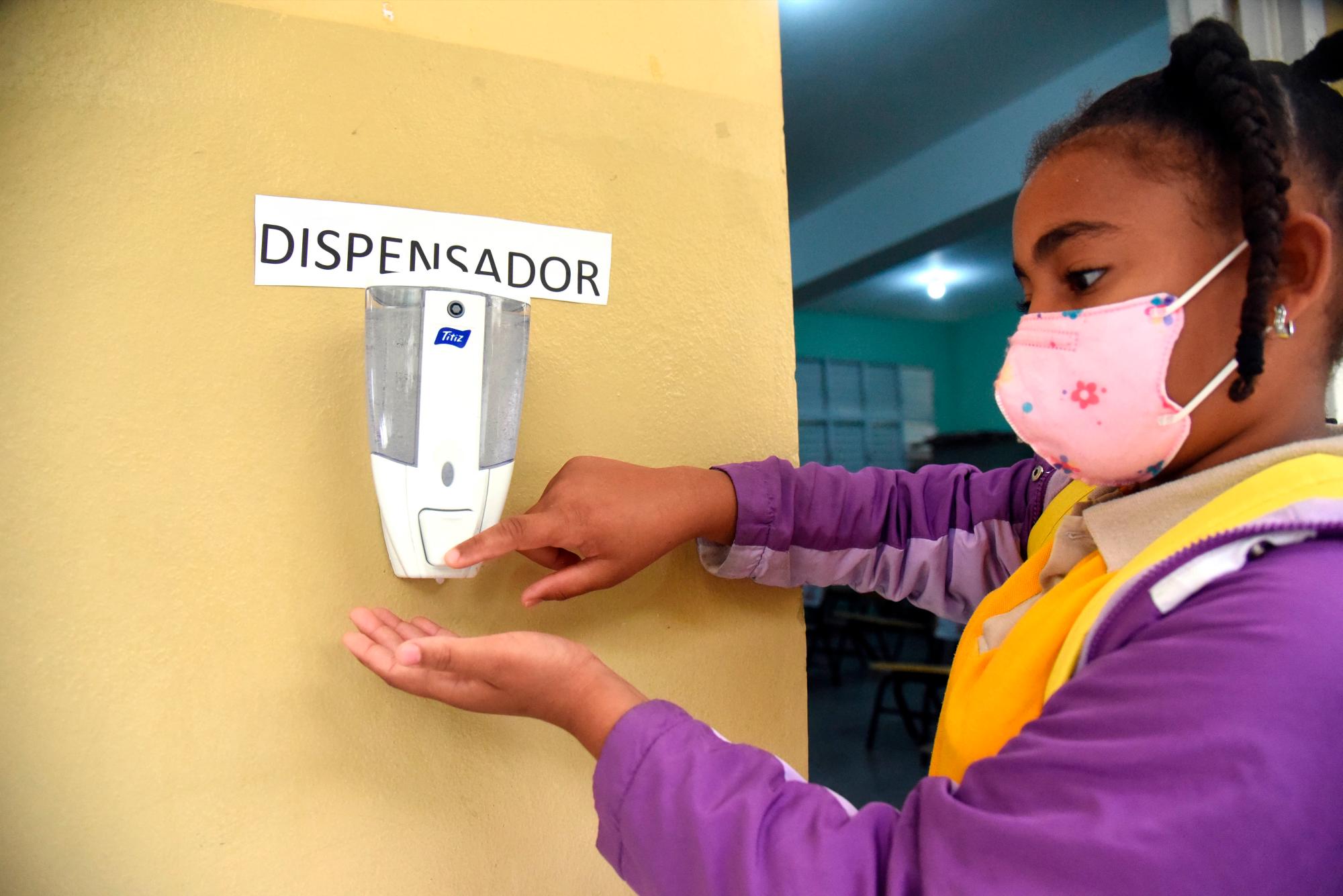 Una estudiante utiliza un dispensador para higienizarse las manos en una de las escuelas en la que se inició hoy el  retorno de las clases.