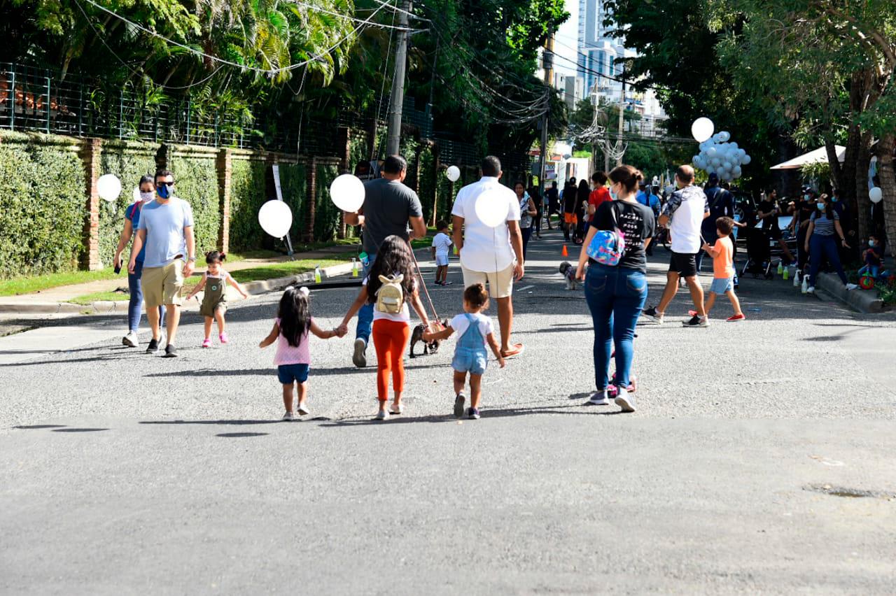 Niños y adultos caminan por calle de Piantini.