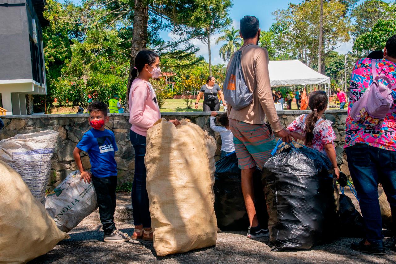 Niños junto a sus padres con sacos de plásticos.