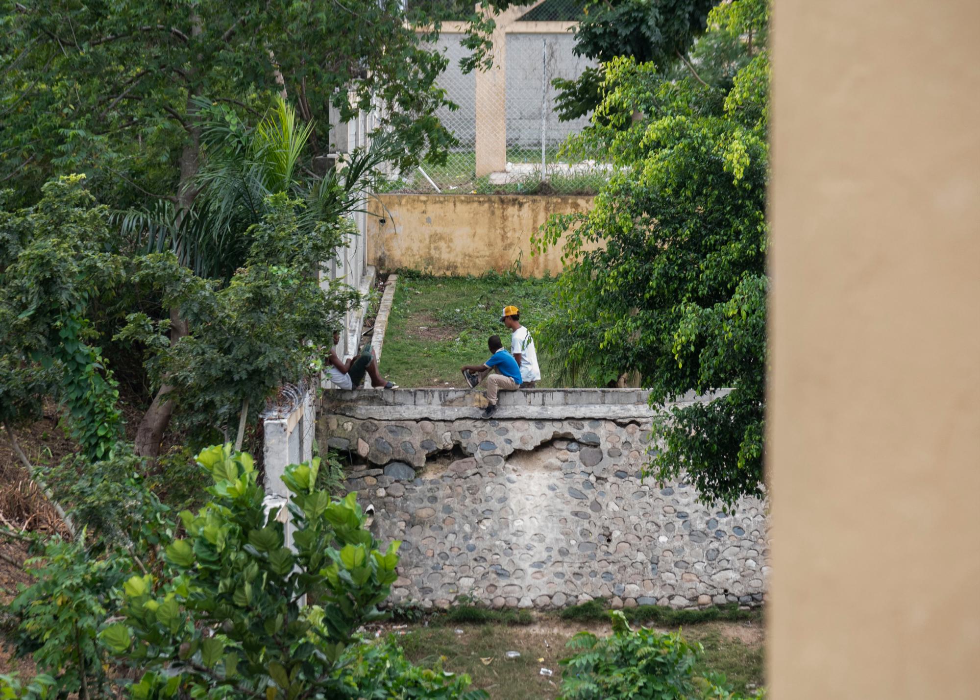 Dos jovenes junto a un estudiante sobre el muro de la escuela María Muñoz Soriano