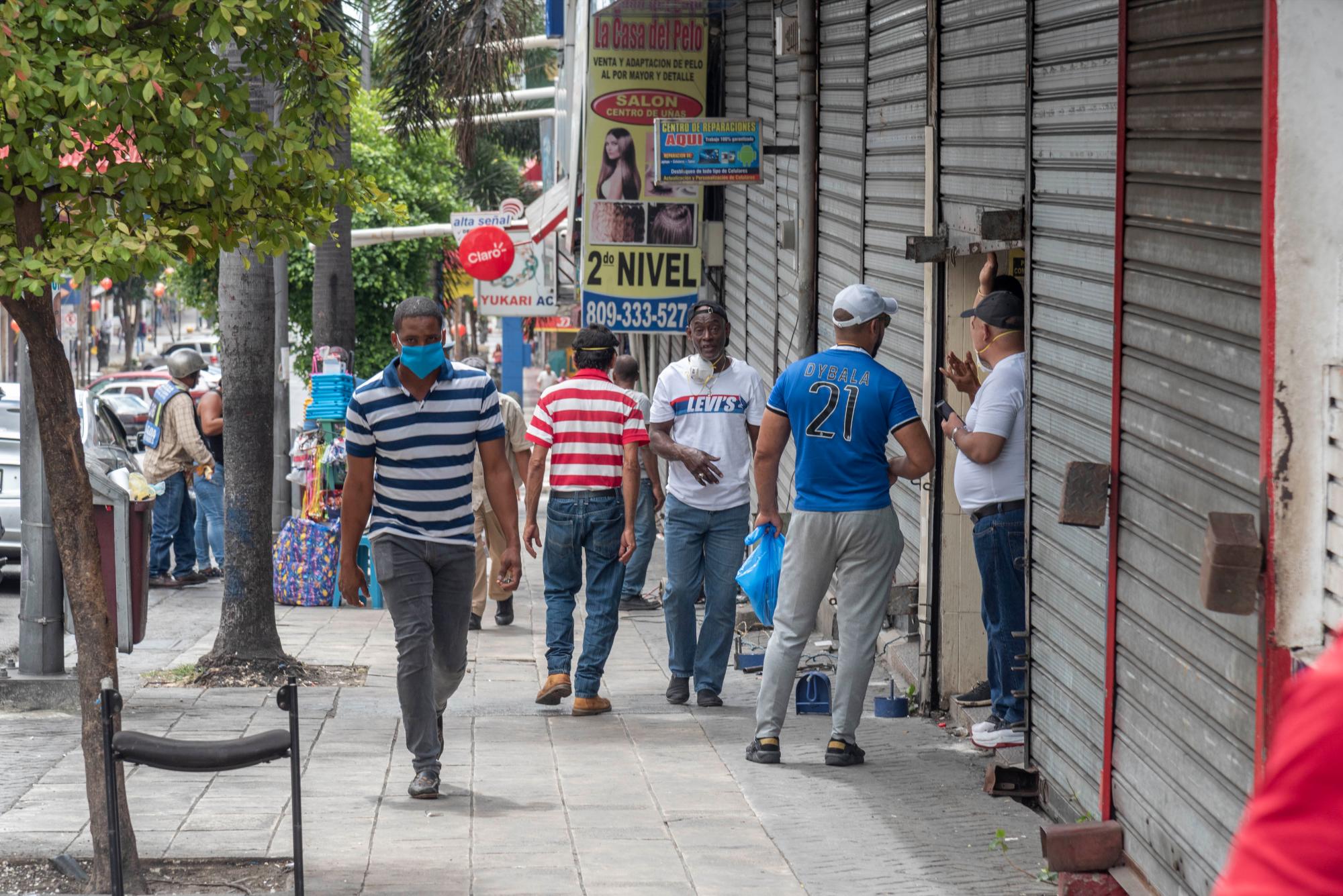 Peatones caminan cerca del Parque Enriquillo con algunas medidas de precaución por el coronavirus.