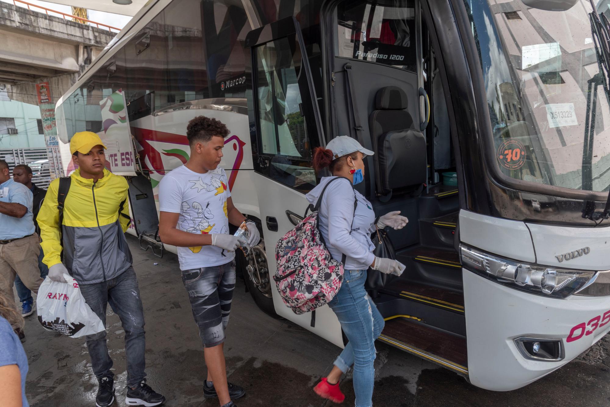 Pasajeros abordan un autobús usando guantes y mascarilla como protección ante el coronavirus.