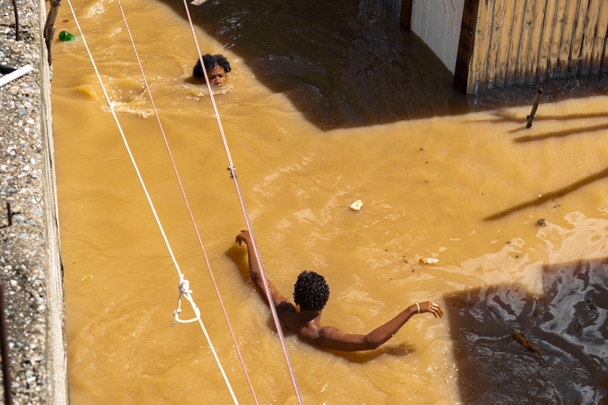 Algunos jóvenes nadan en medio de las inundaciones.