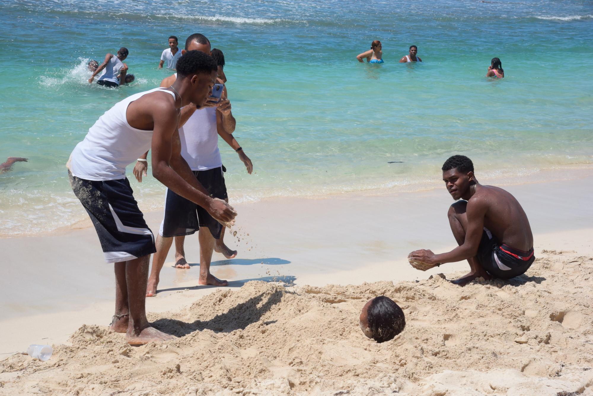 Jóvenes juegan en la arena en la playa de Guayacanes.