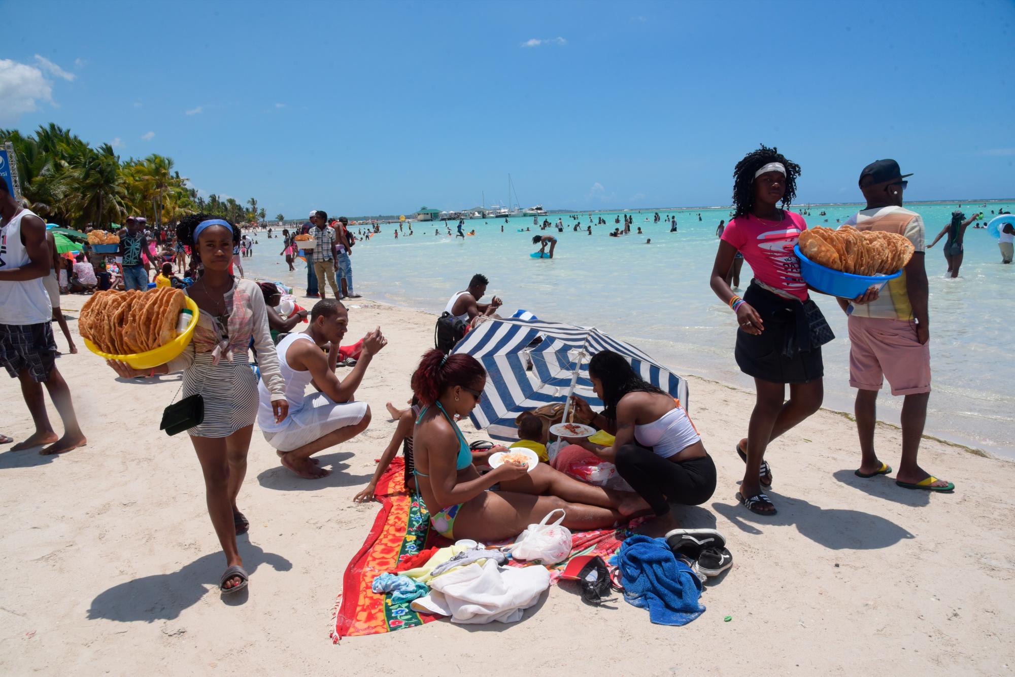 Personas y vendedores en la playa de Boca Chica.
