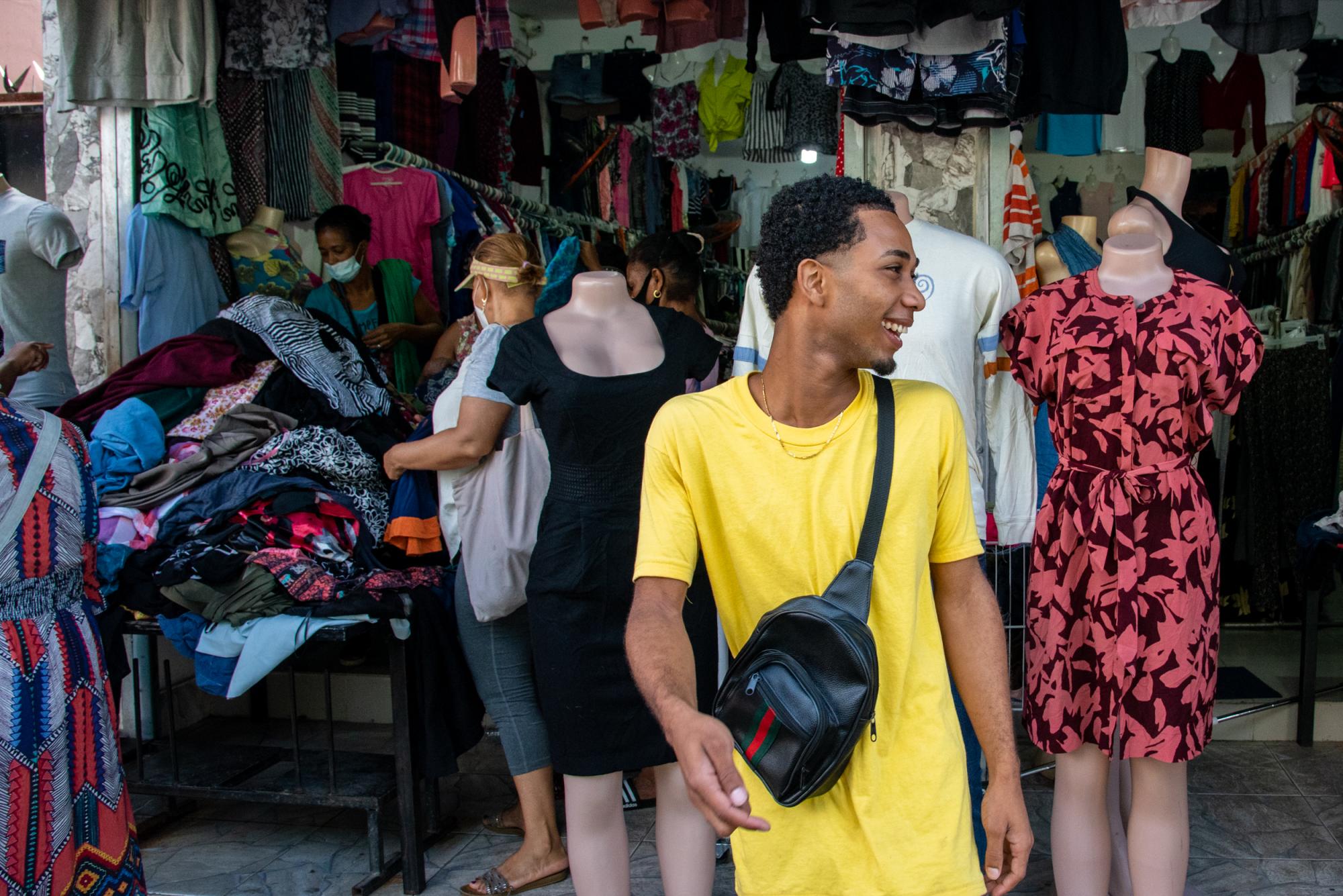 Un joven camina sonriente frente a uno de los comercios en los que se vende ropa de paca (Foto: Juan Miguel Peña)