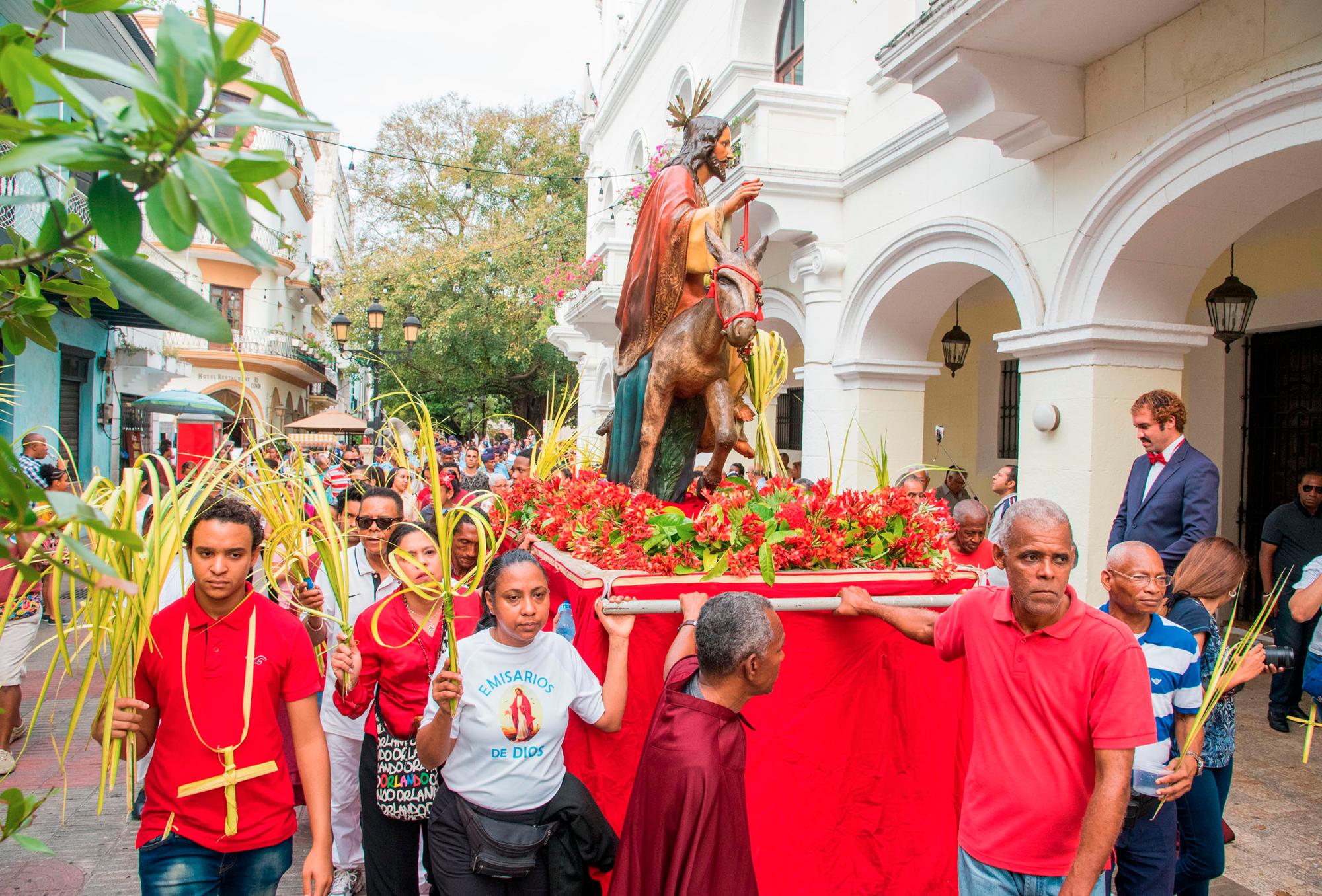 Feligreses guían el carro con la imagen de Jesús encima del burro.