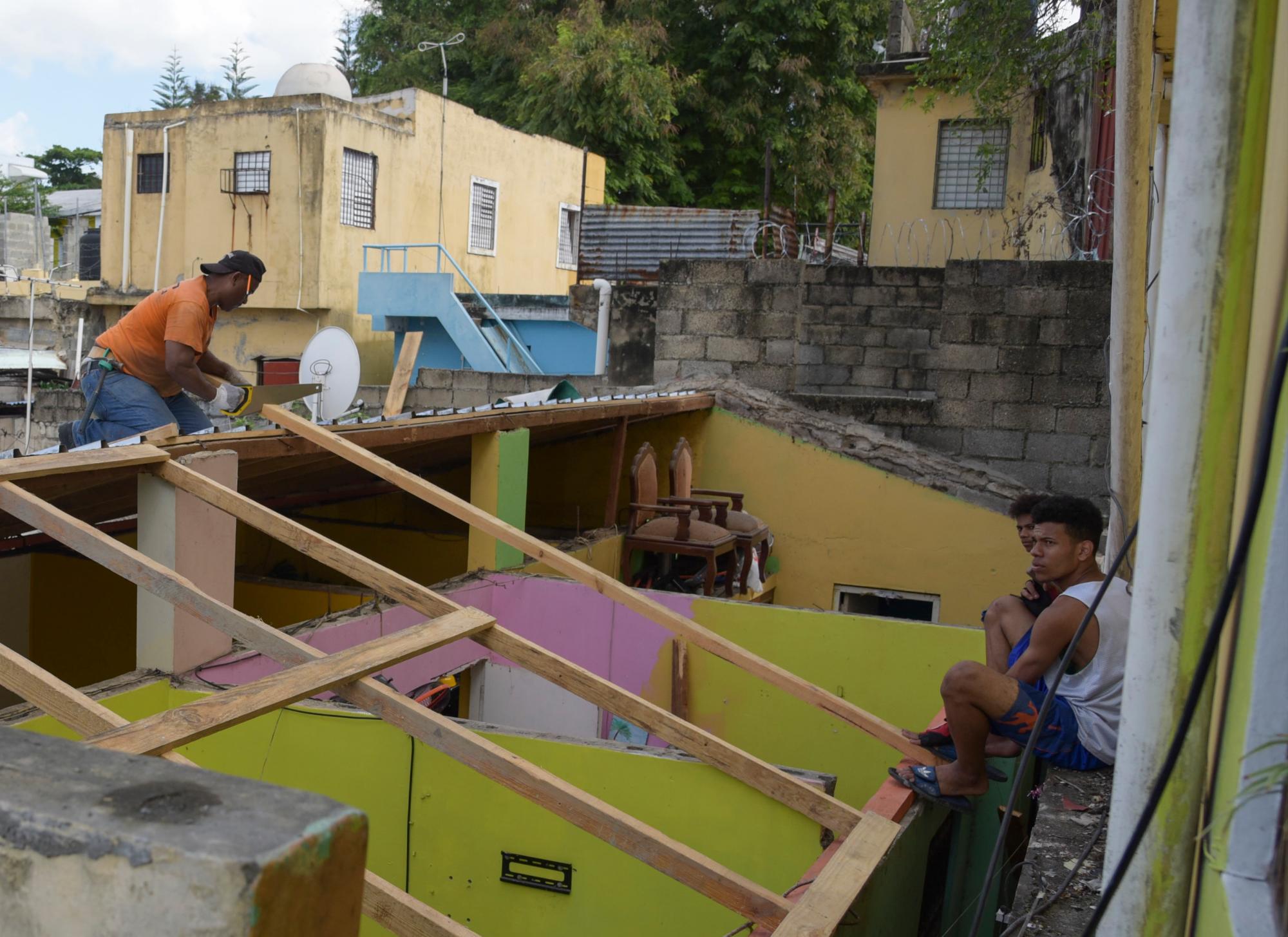 Un carpinteros repara una de las casas cuyo techo de zinc fue dañado por bloques lanzados al aire durante la explosión en Polyplas.