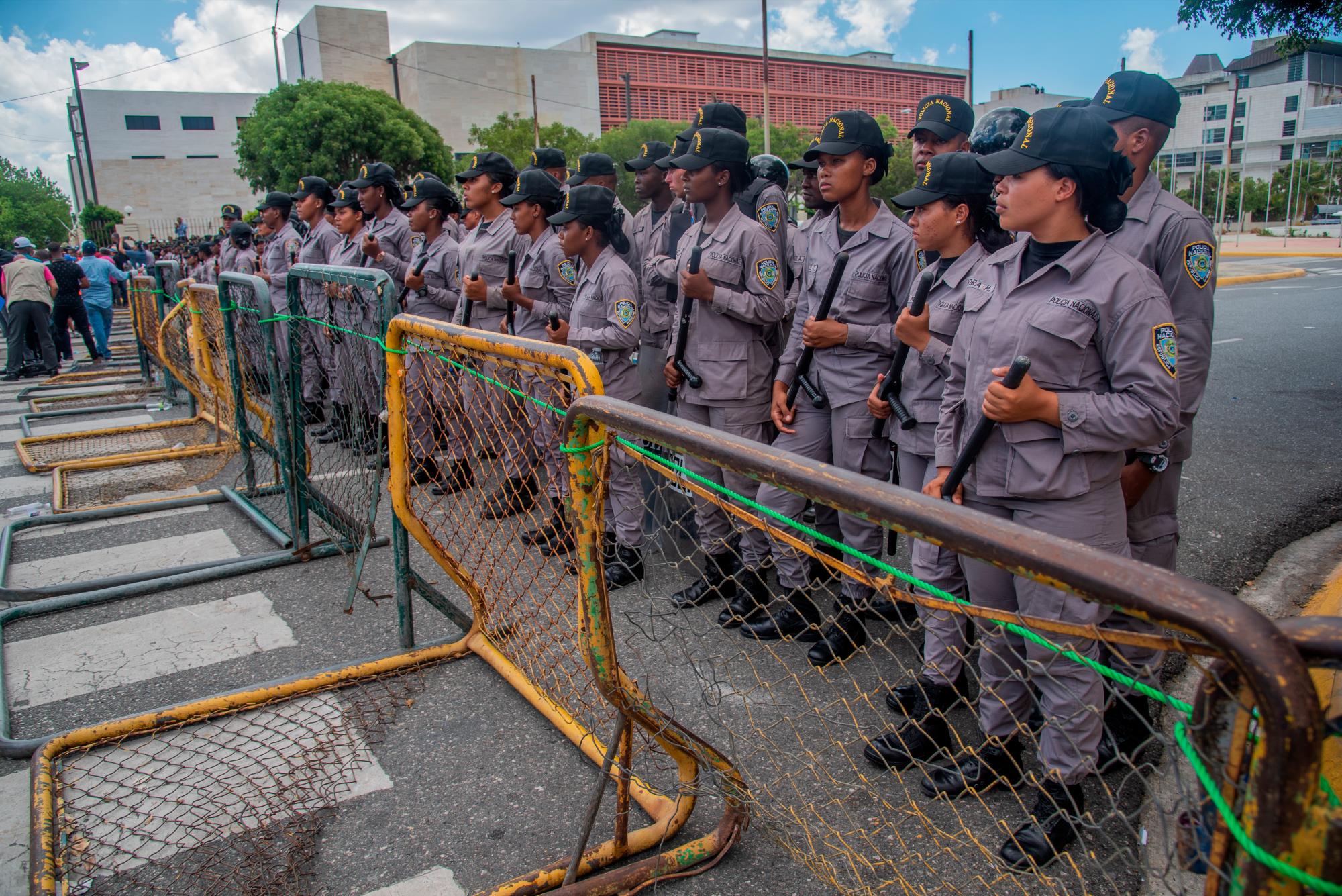 Agentes policiales se mantienen firmes en su posición mientras observan la llegada de manifestantes en la marcha concentración hacia el Congreso Nacional de seguidores del precandidato presidencial del PRM, Luis Abinader