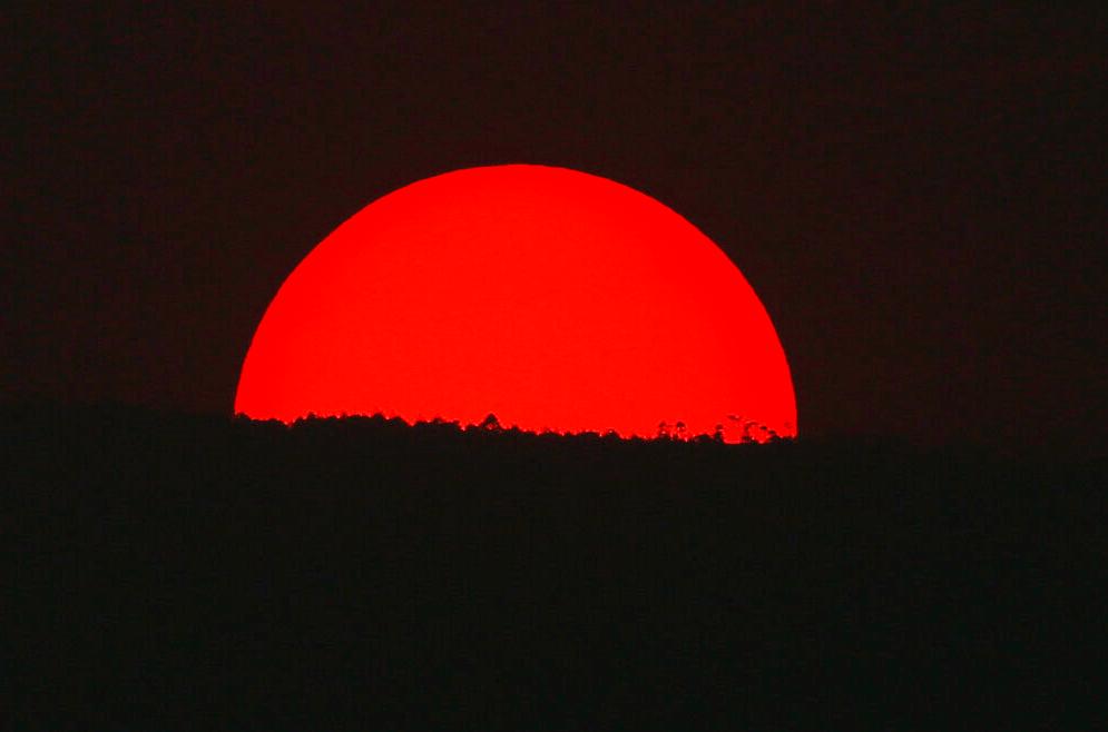 Teñido de rojo por una espesa nube de humo y contaminación, el sol se pone sobre las montañas de la Ciudad de México, el lunes 13 de mayo de 2019.