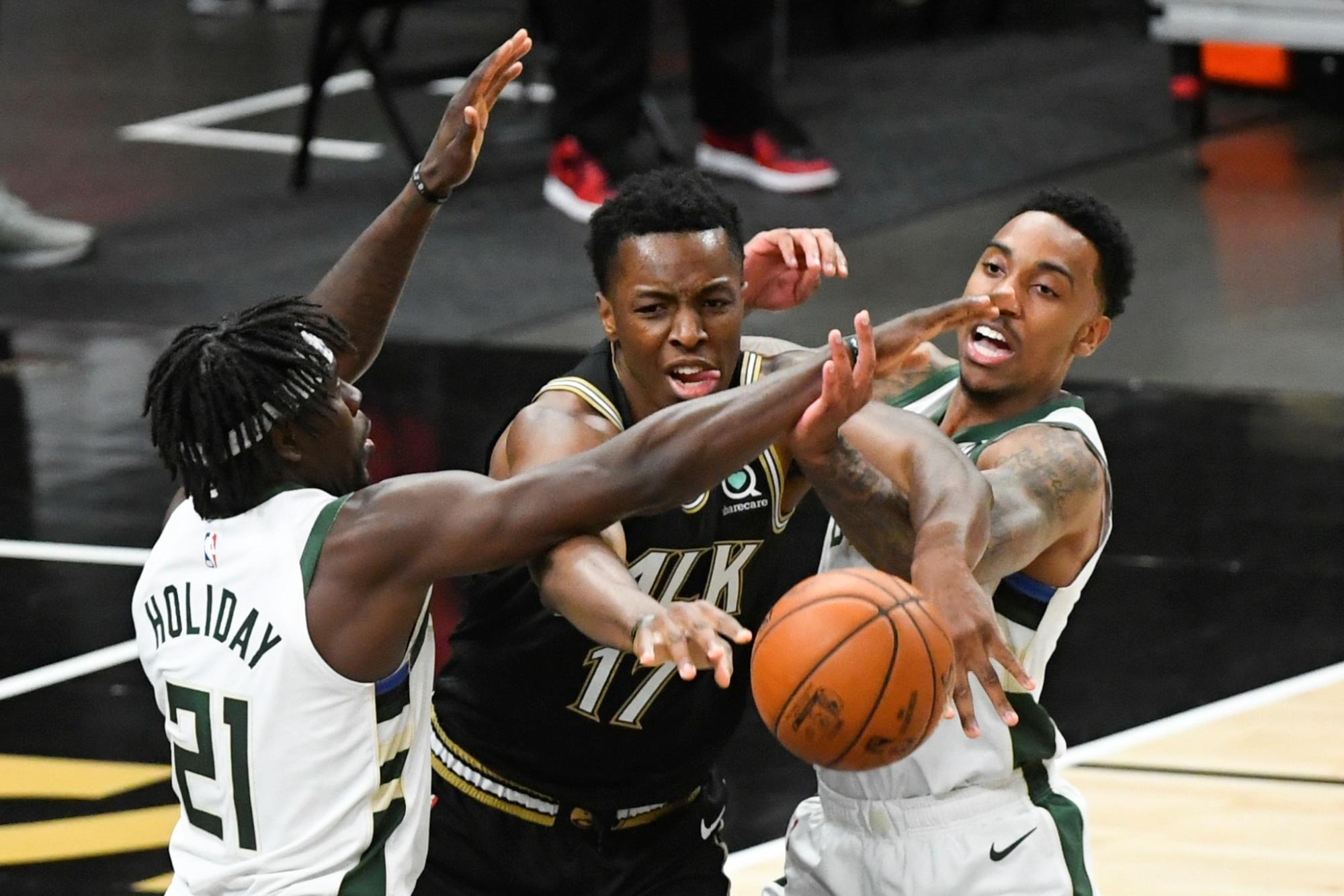 El delantero de los Atlanta Hawks, Onyeka Okongwu, pasa bajo la presión del base de los Milwaukee Bucks, Jrue Holiday (izq.) y del escolta Jeff Teague (der.) Durante el sexto juego de las finales de la Conferencia Este de la NBA el 03 de julio de 2021. (EFE/EPA/John Amis Shutterstock)