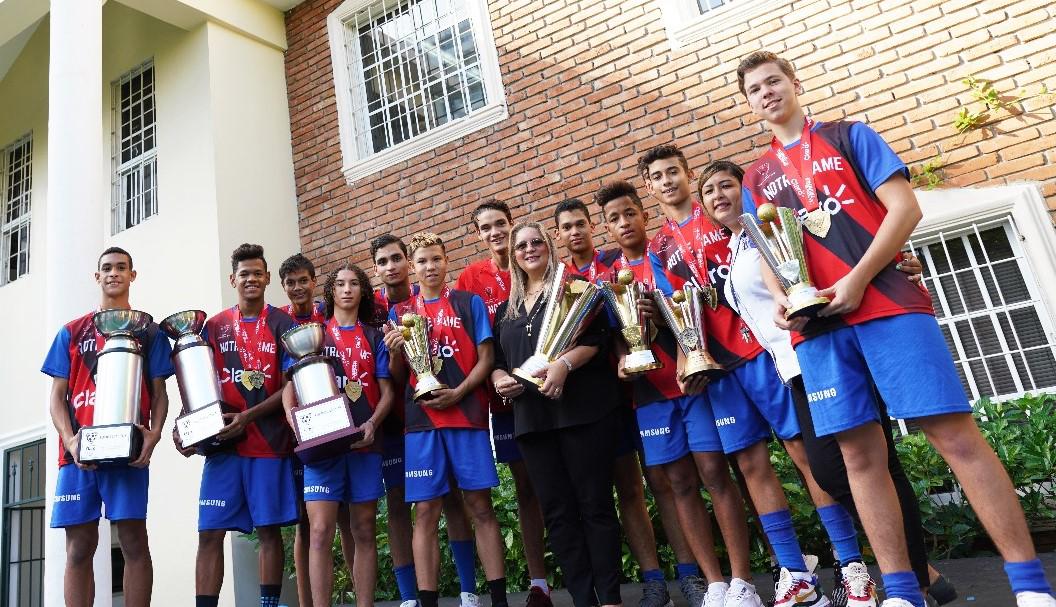 Los jugadores del equipo con las ocho copas ganadas por los equipos masculino y femenino del Notre Dame (Fuente externa).
