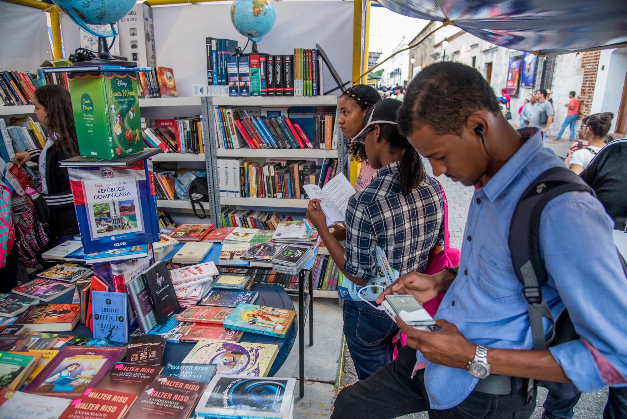 Algunos visitantes consultan y averiguan sobre los libros en oferta